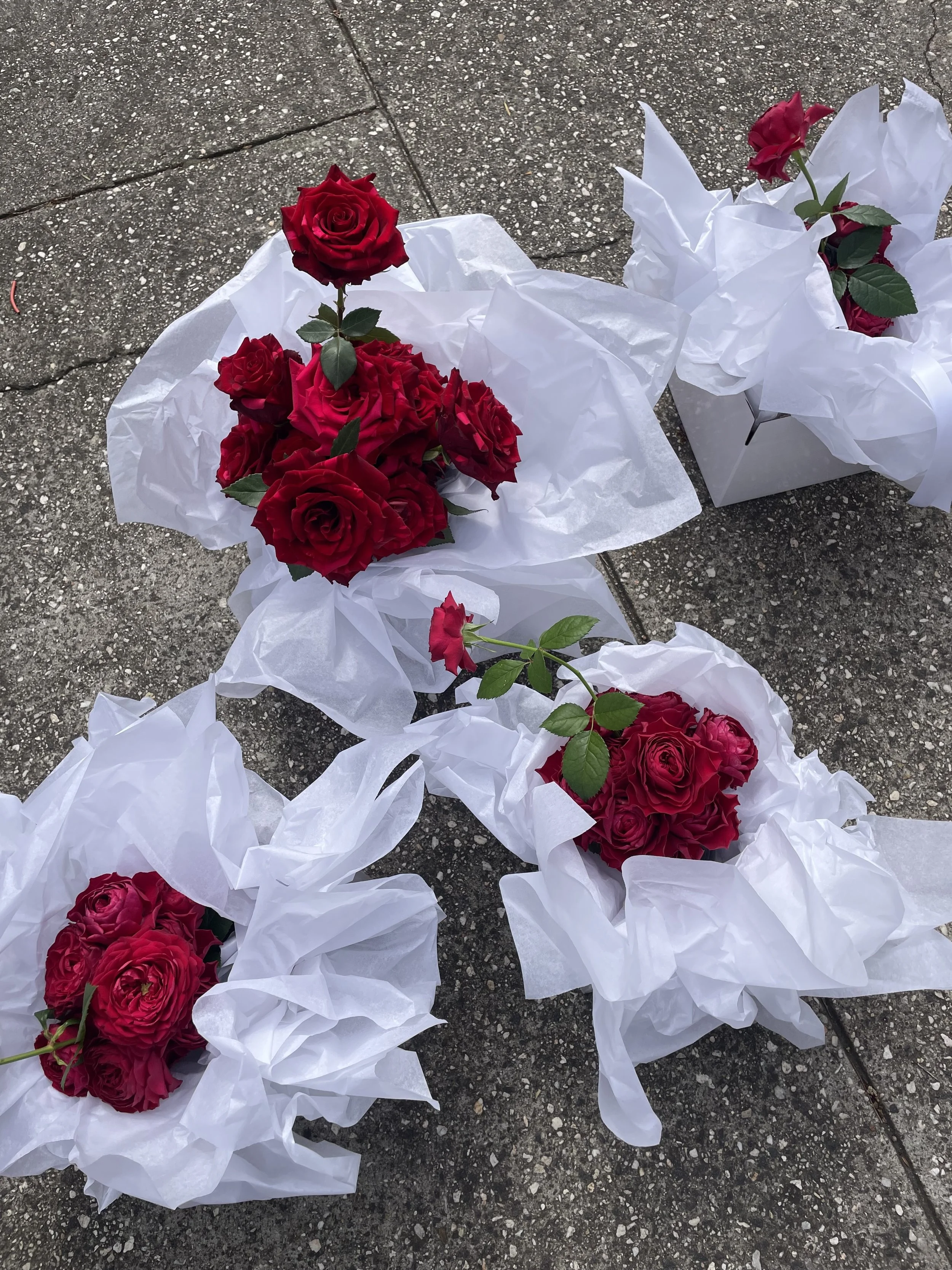 Bridal party flowers for Honey Honey couple Christian and Lydia's wedding featuring undulating red roses wrapped in clouds of white tissue paper