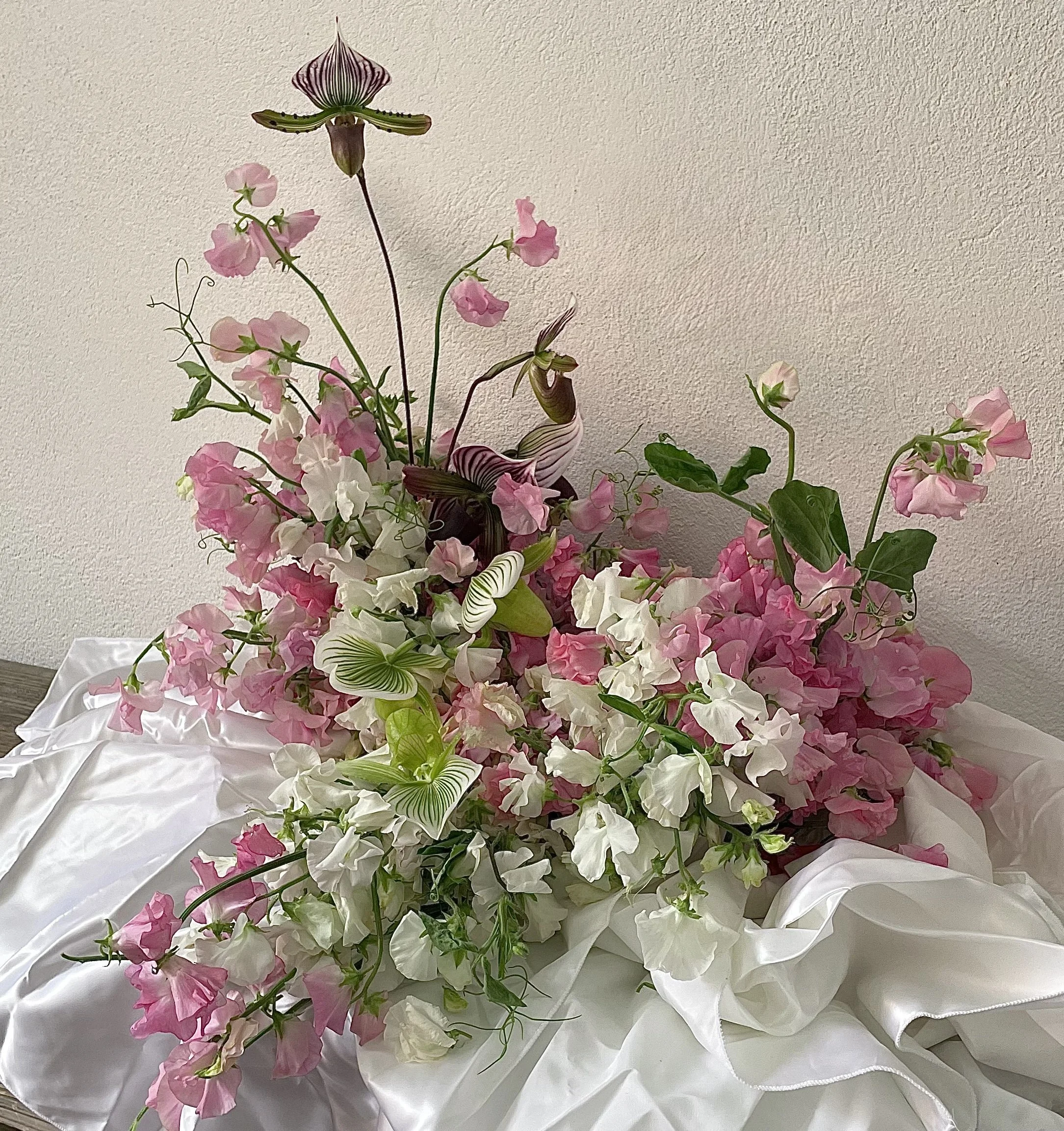 Honey Honey arrangement featuring mounds of sweetpea in white and pink shades and tumbling slipper orchids