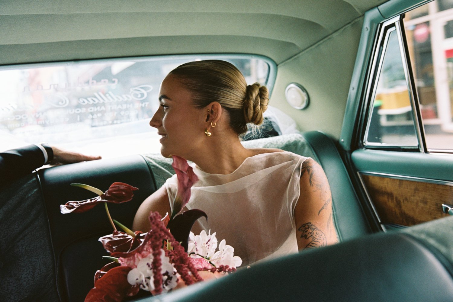 Gorgeous bride holding moody bouquet in the back of a Cadillac. Image shot by Ceremony By Charlie