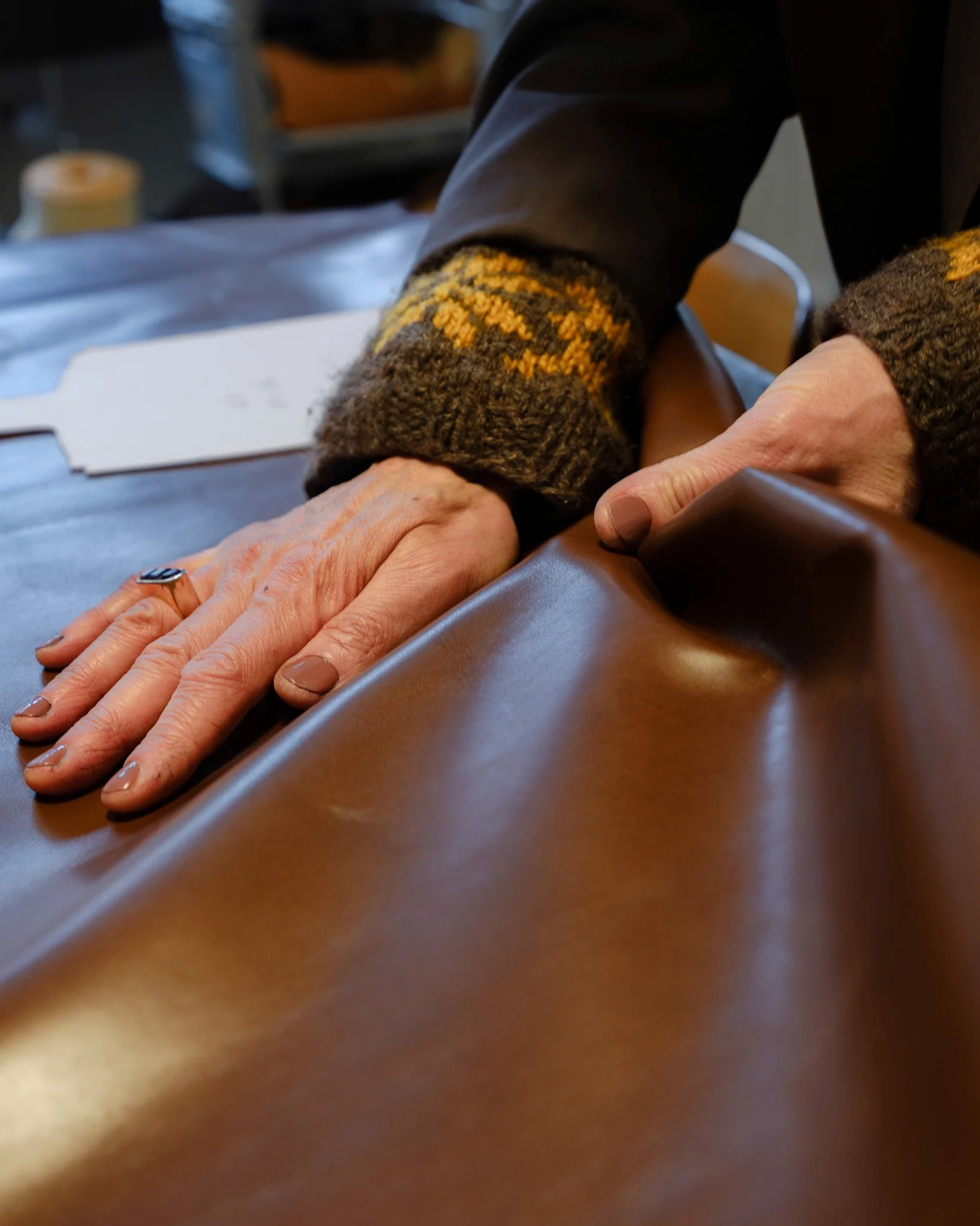 Mains posées sur du cuir en atelier, Blanche, Bâle; Hands resting on leather in the workshop, Blanche, Basel; Hände auf Leder in der Werkstatt, Blanche in Basel