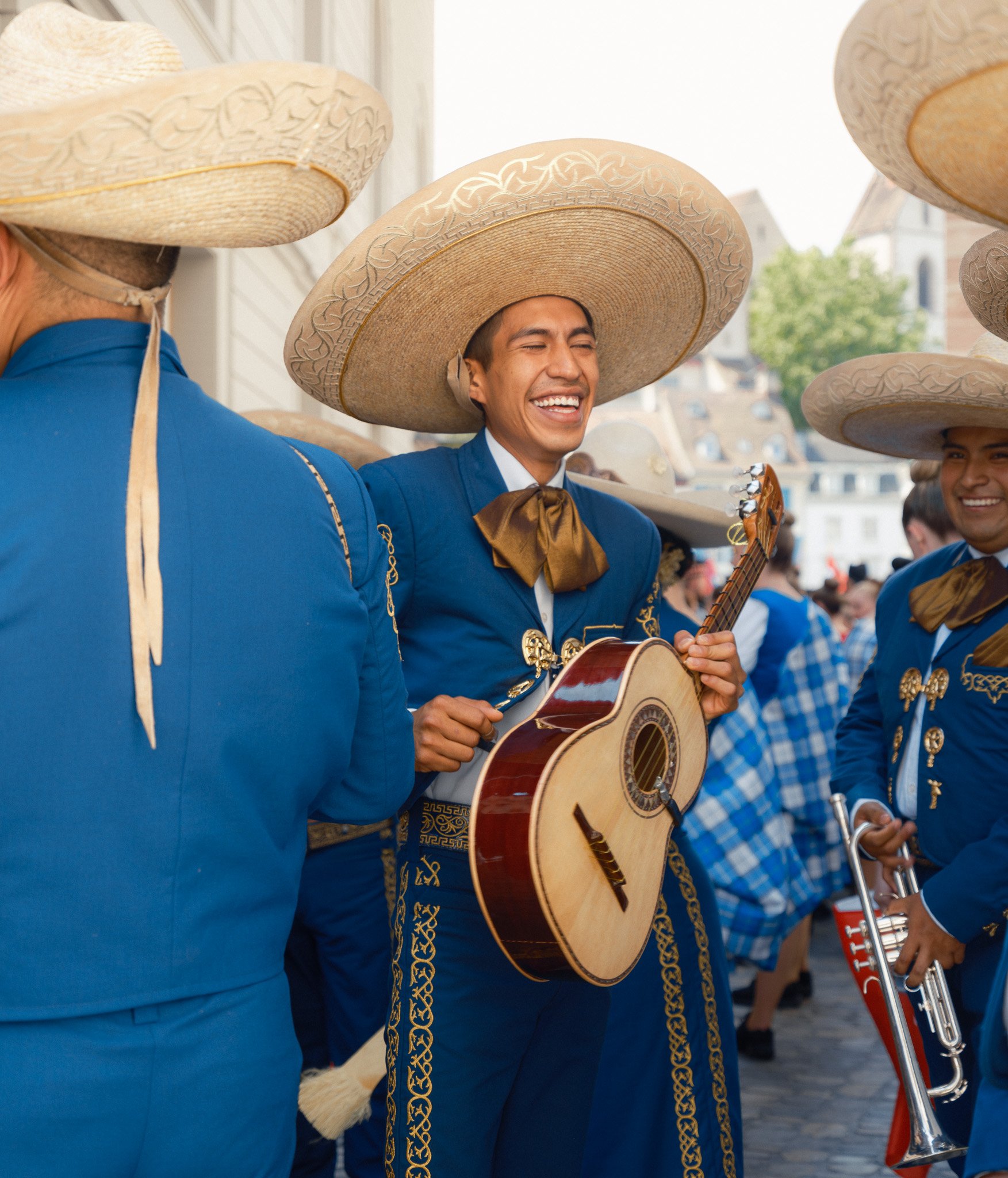 Photographie de Antoine Georgelin, portrait d'un musicien mexicain portant une guitare rigolant avec d'autres musiciens à Bâle, Suisse. Fotografie von Antoine Georgelin, Porträt eines mexikanischen Musikers, der in Basel, Schweiz, eine Gitarre trägt