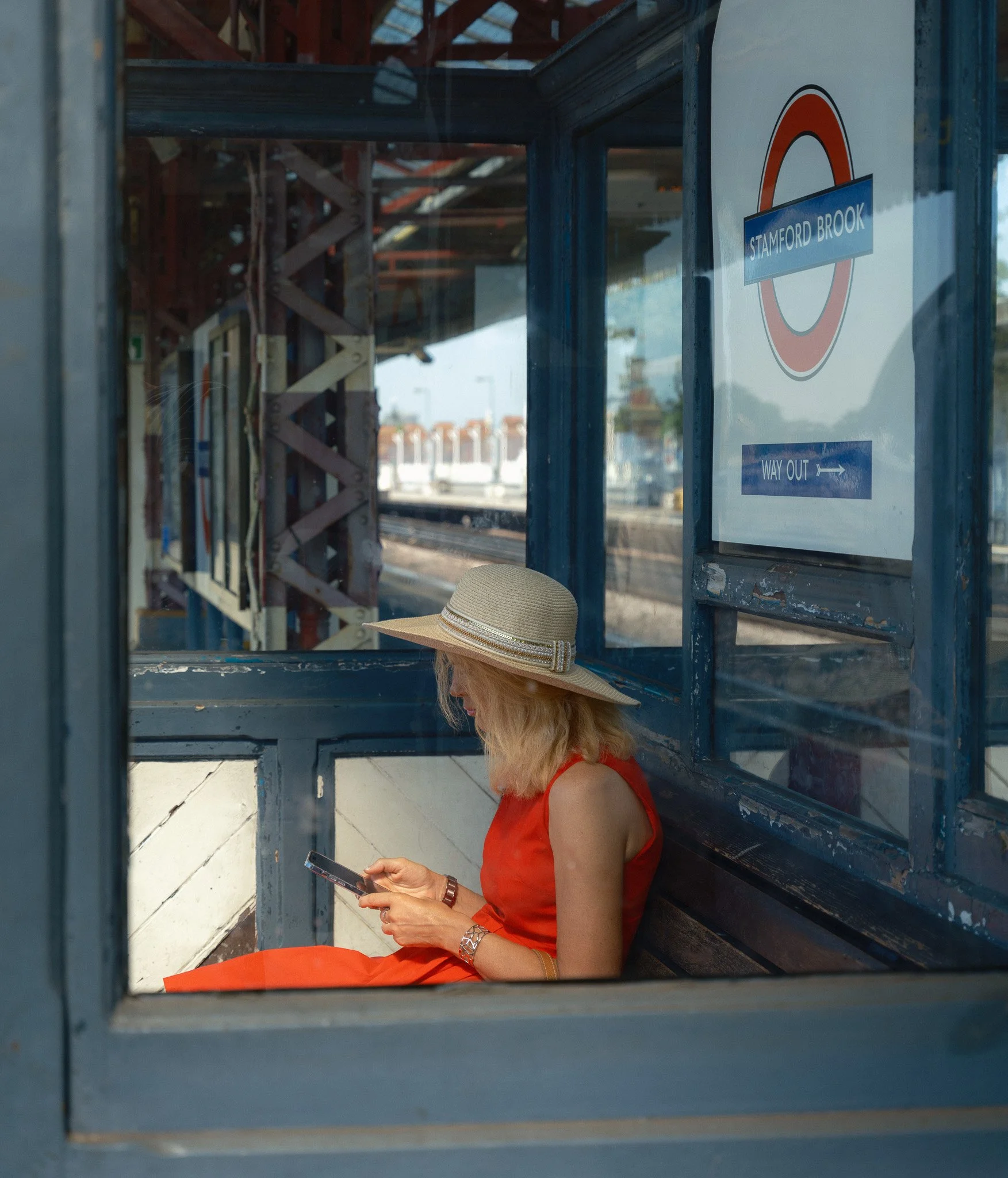 Photographie par Antoine Georgelin, une femme attend assise son train dans une gare de Londres, Angleterre. Fotografie von Antoine Georgelin, eine Frau wartet sitzend auf ihren Zug an einem Bahnhof in London, England.