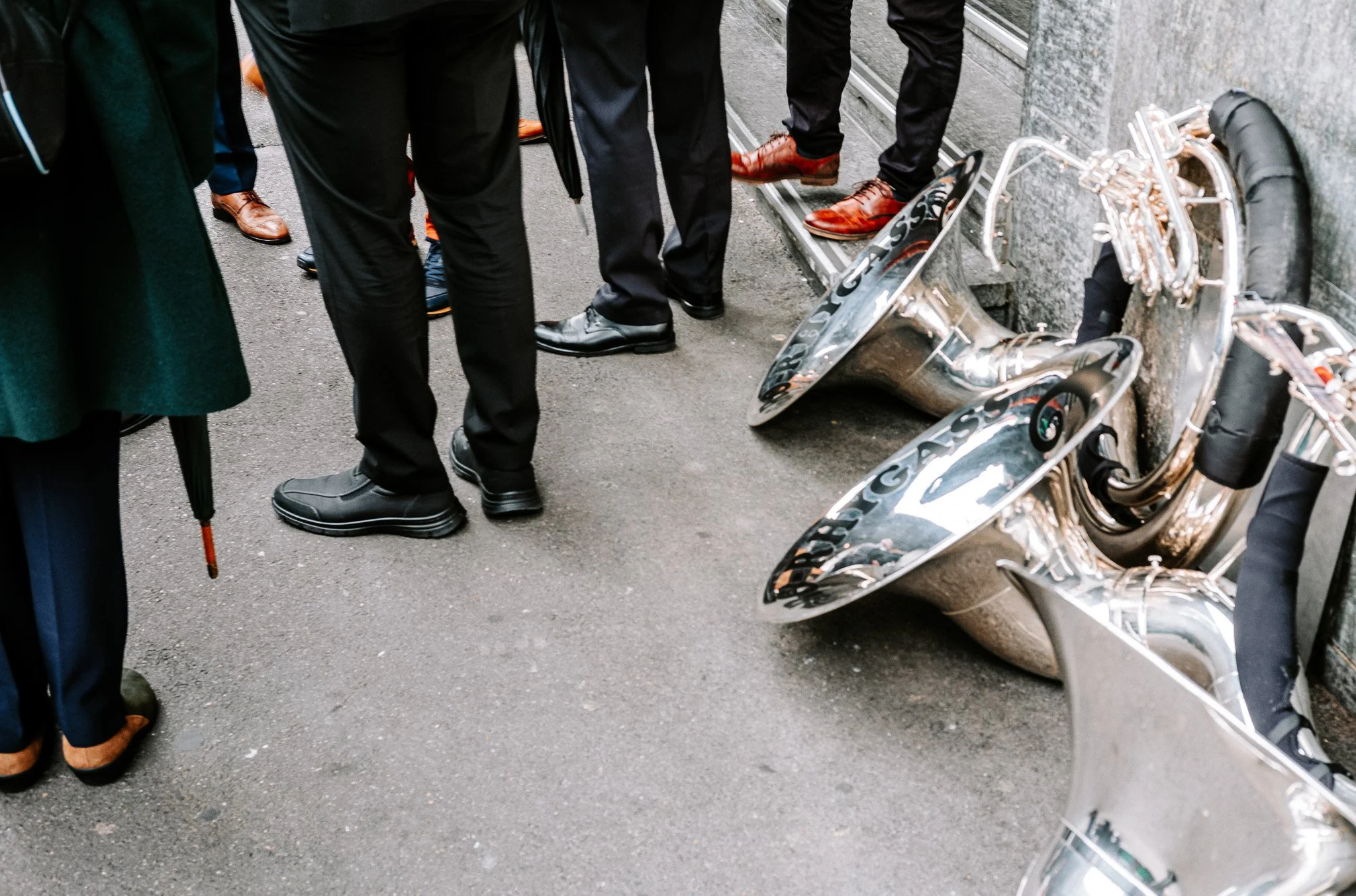 Photographie de rue durant le carnaval de Bâle, des hommes ont posés leurs instruments dans la rue. Fotografie einer Straßenszene während des Basler Karnevals, bei der Männer ihre Instrumente auf der Straße abgestellt haben.