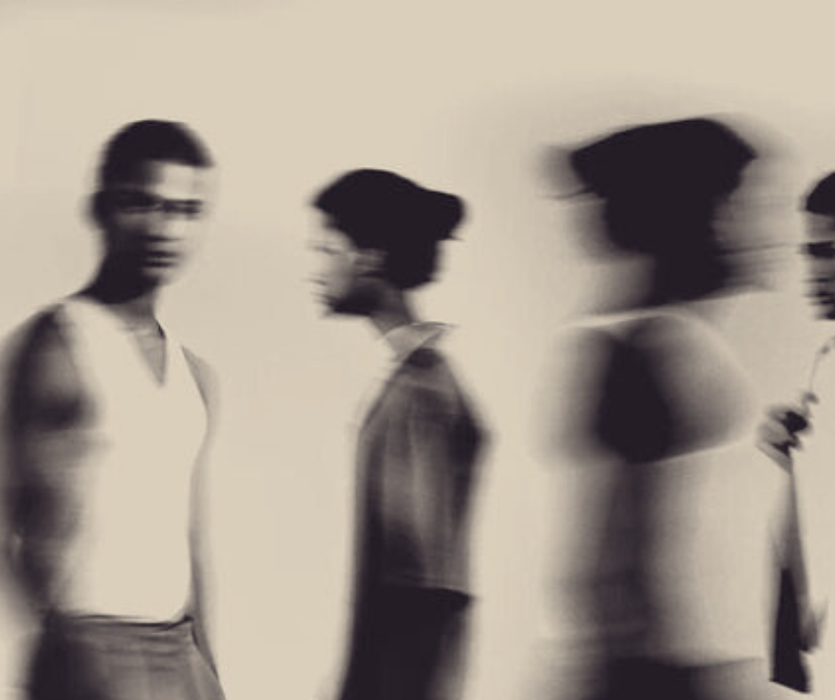 Blurred black-and-white photo of four women standing in profile against a plain background, with motion blur conveying movement.