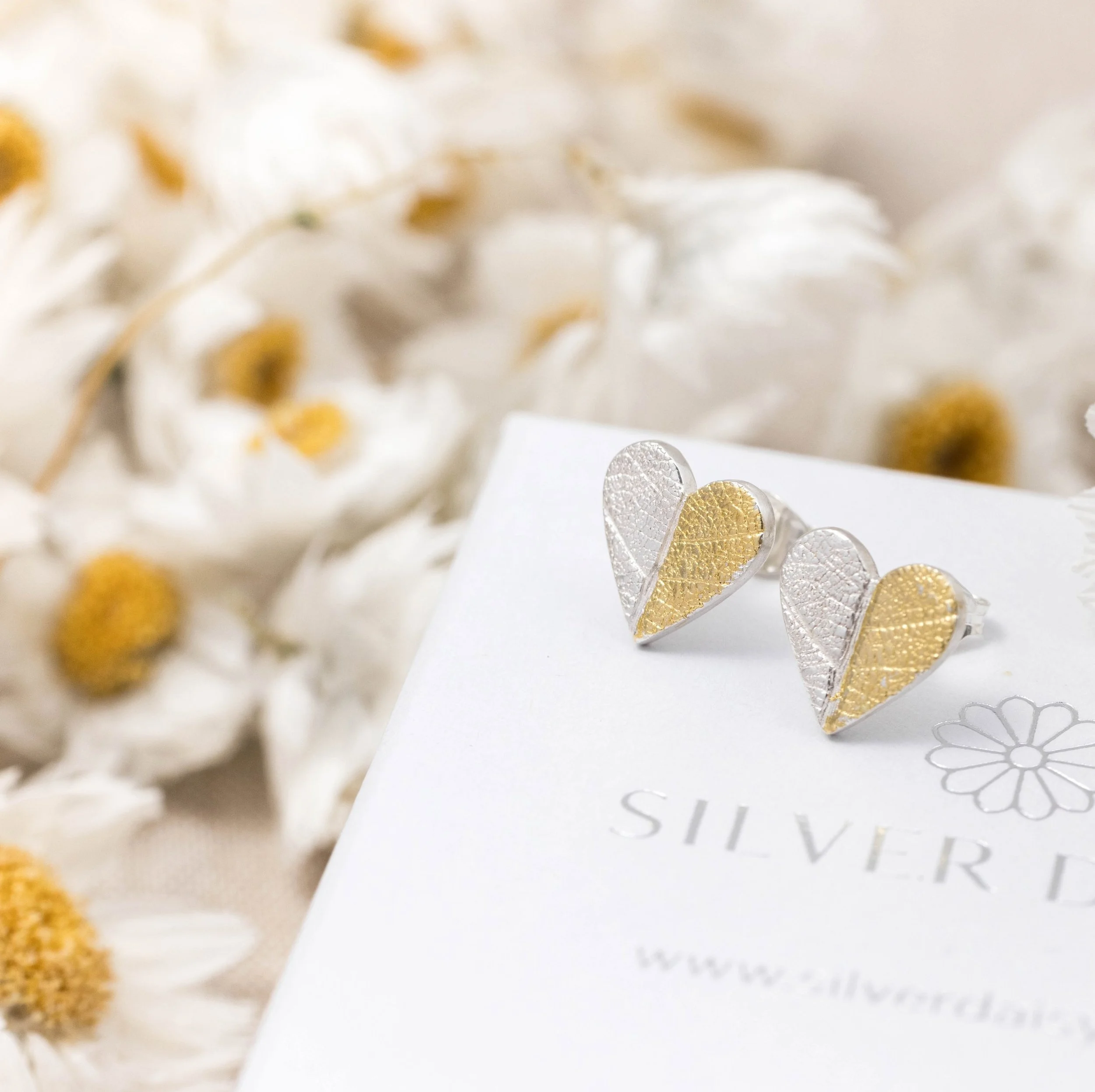 Sterling silver heart-shaped stud earrings with textured leaf pattern and gold keum-boo accents.