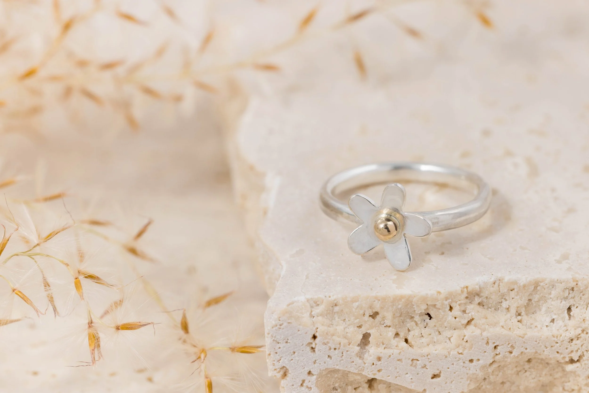 Sterling silver daisy ring with a polished band and detailed medium-sized flower design featuring 9ct gold stamen and a domed centre.