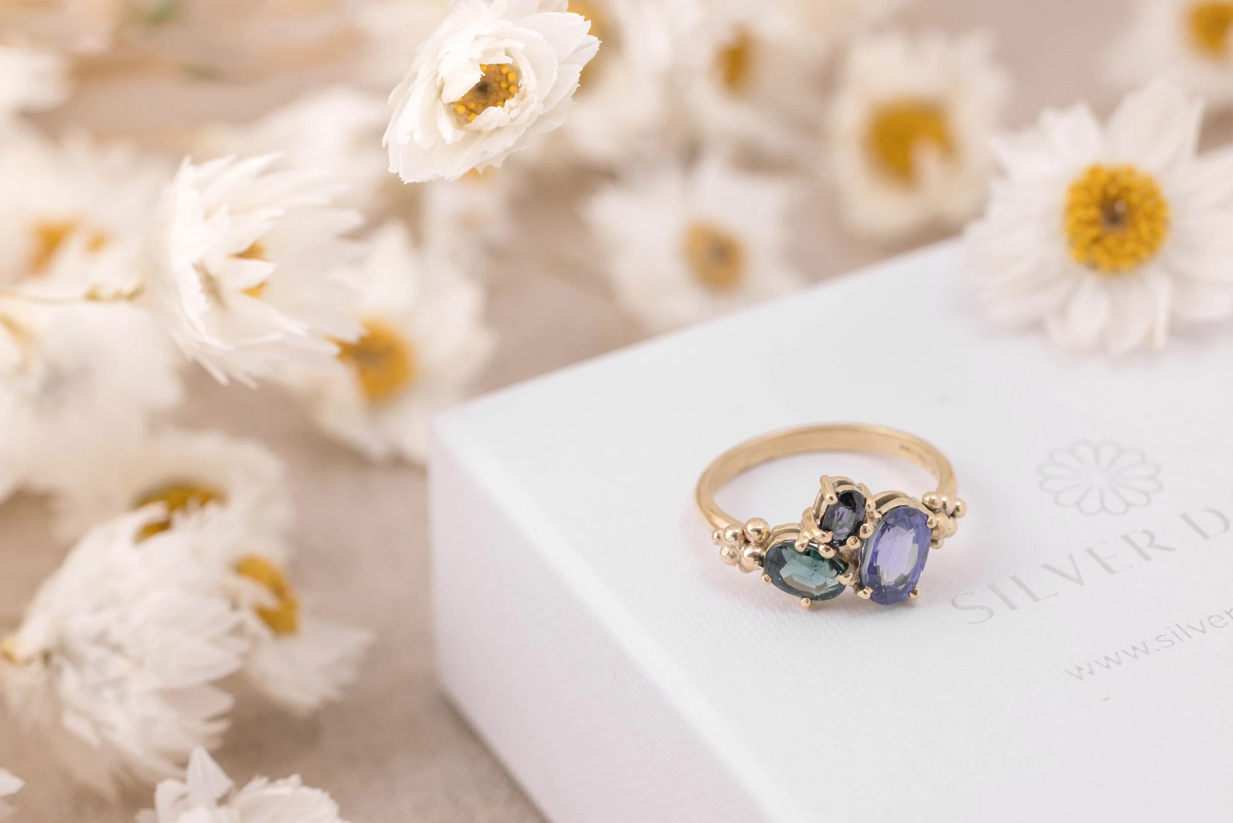 Yellow gold ring with a cluster of sparkling saaphires in teal, deep blue, and purple. Inspired by the colours of the aurora borealis.