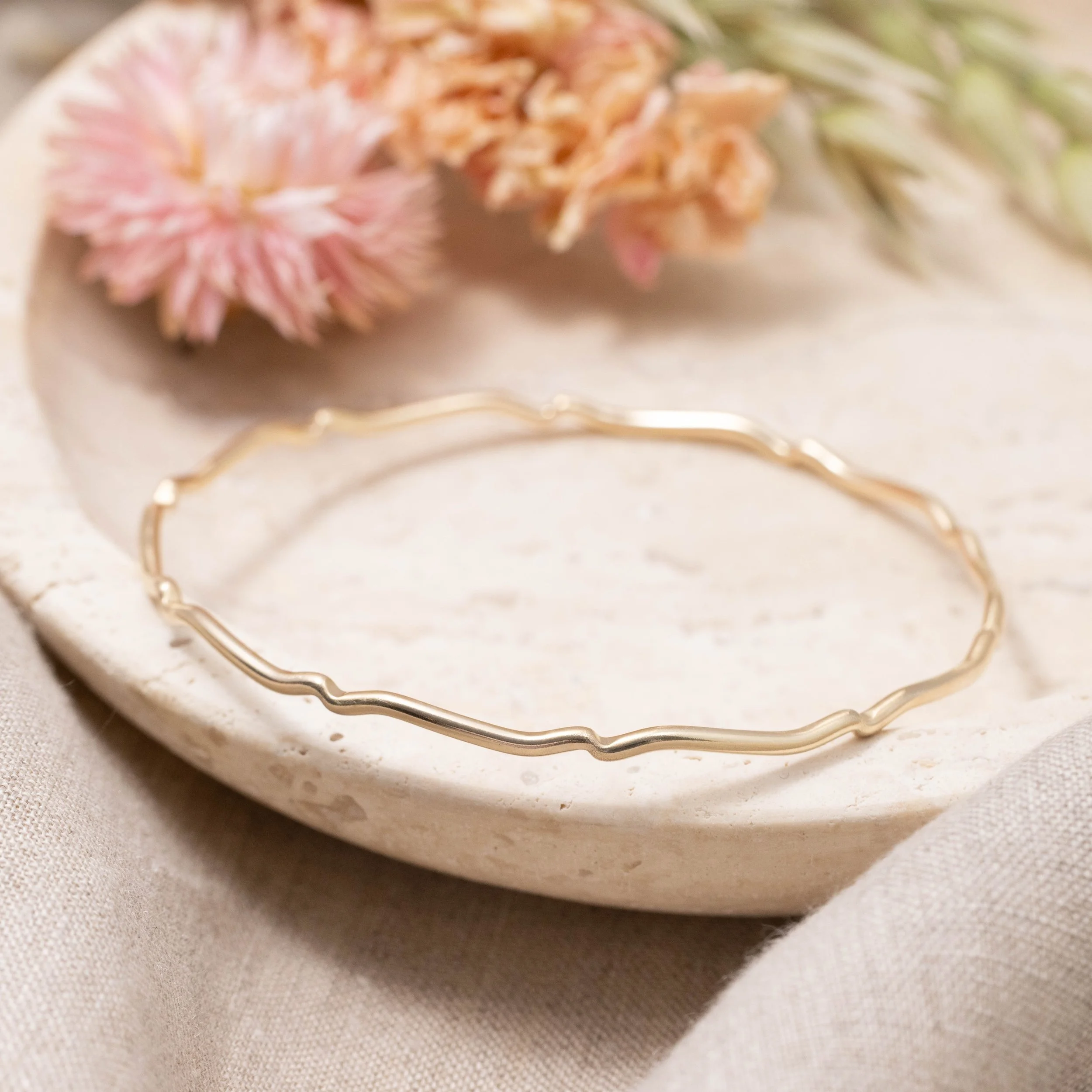 9ct yellow gold scallop bangle with a smooth polished finish and subtle scalloped edge, designed for elegant stacking and everyday wear.