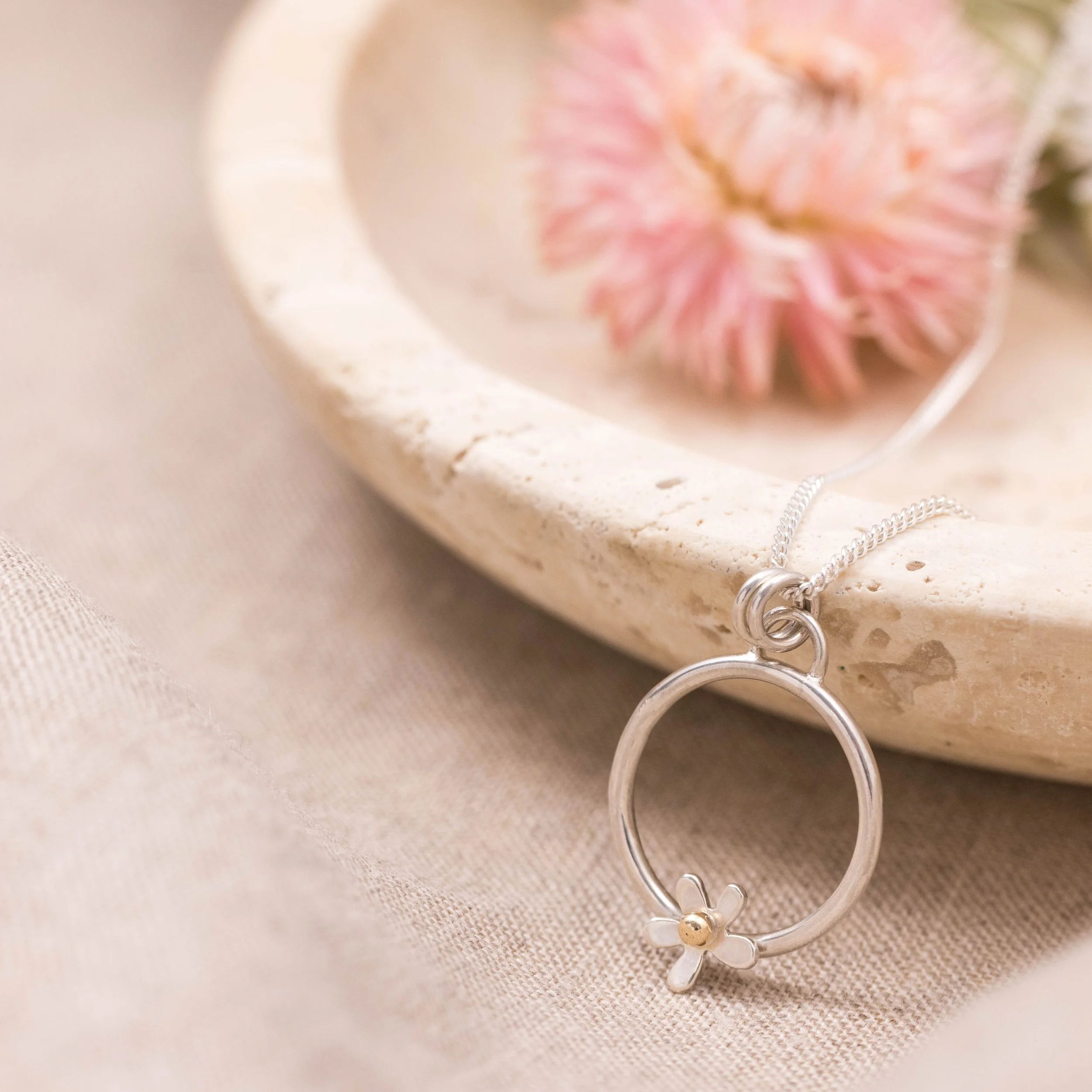 Sterling silver hoop pendant necklace with an open daisy flower design featuring a 9ct gold stamen on a fine chain, polished finish, minimalist floral jewellery.