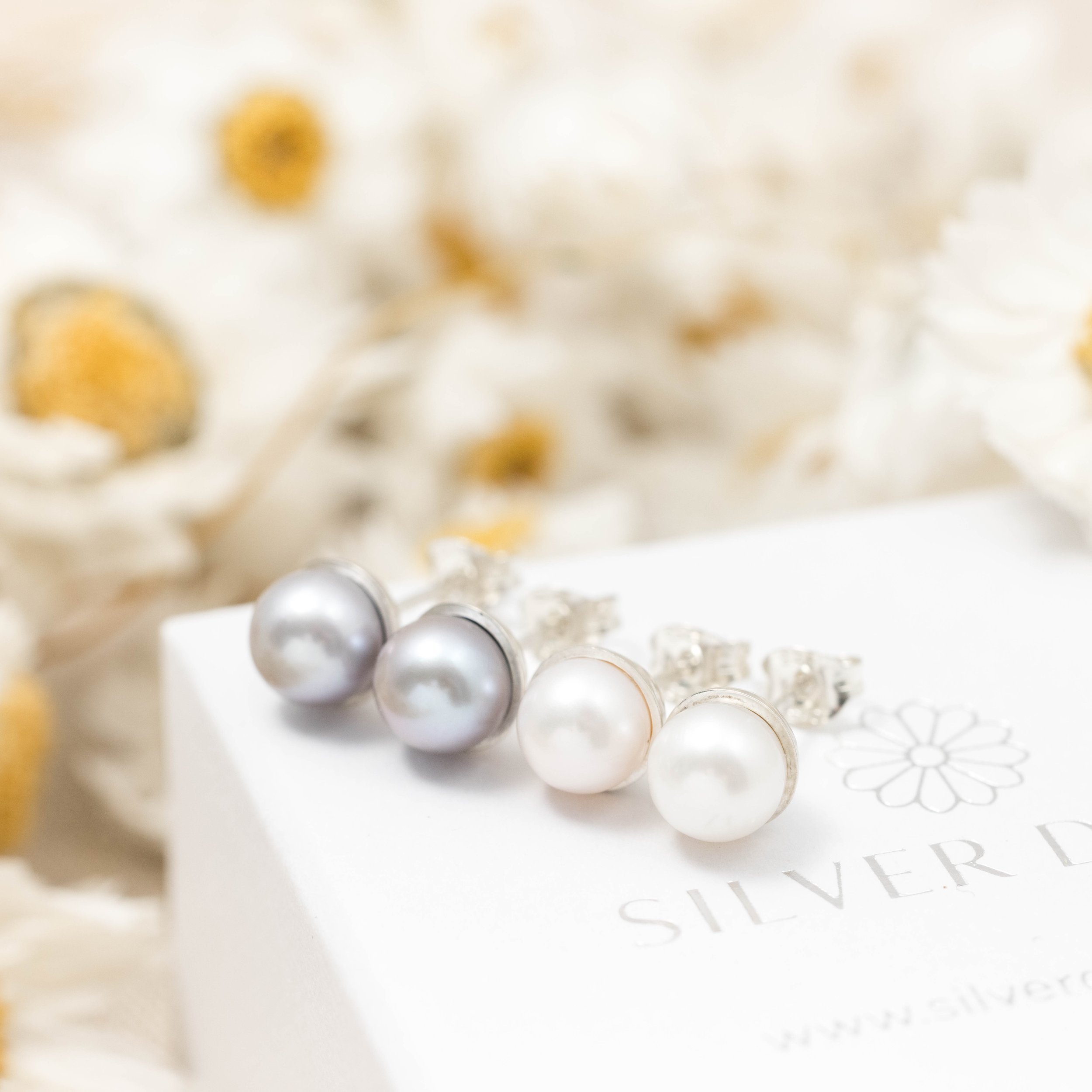 Round ivory freshwater pearl stud earrings with smooth lustrous finish set in handcrafted sterling silver cups with ear post and scroll backs.