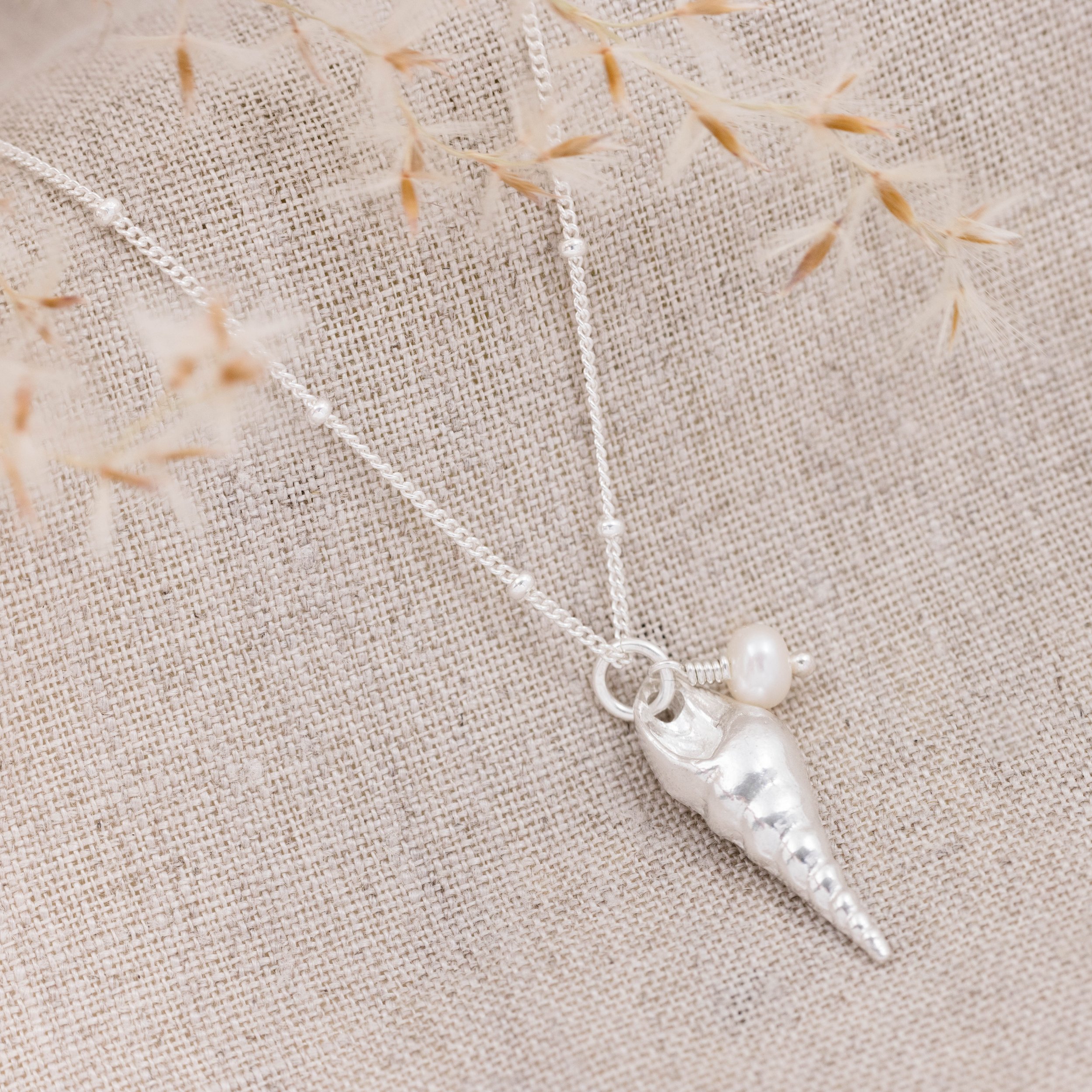 Sterling silver unicorn shell pendant necklace with a single round white pearl on a delicate chain.