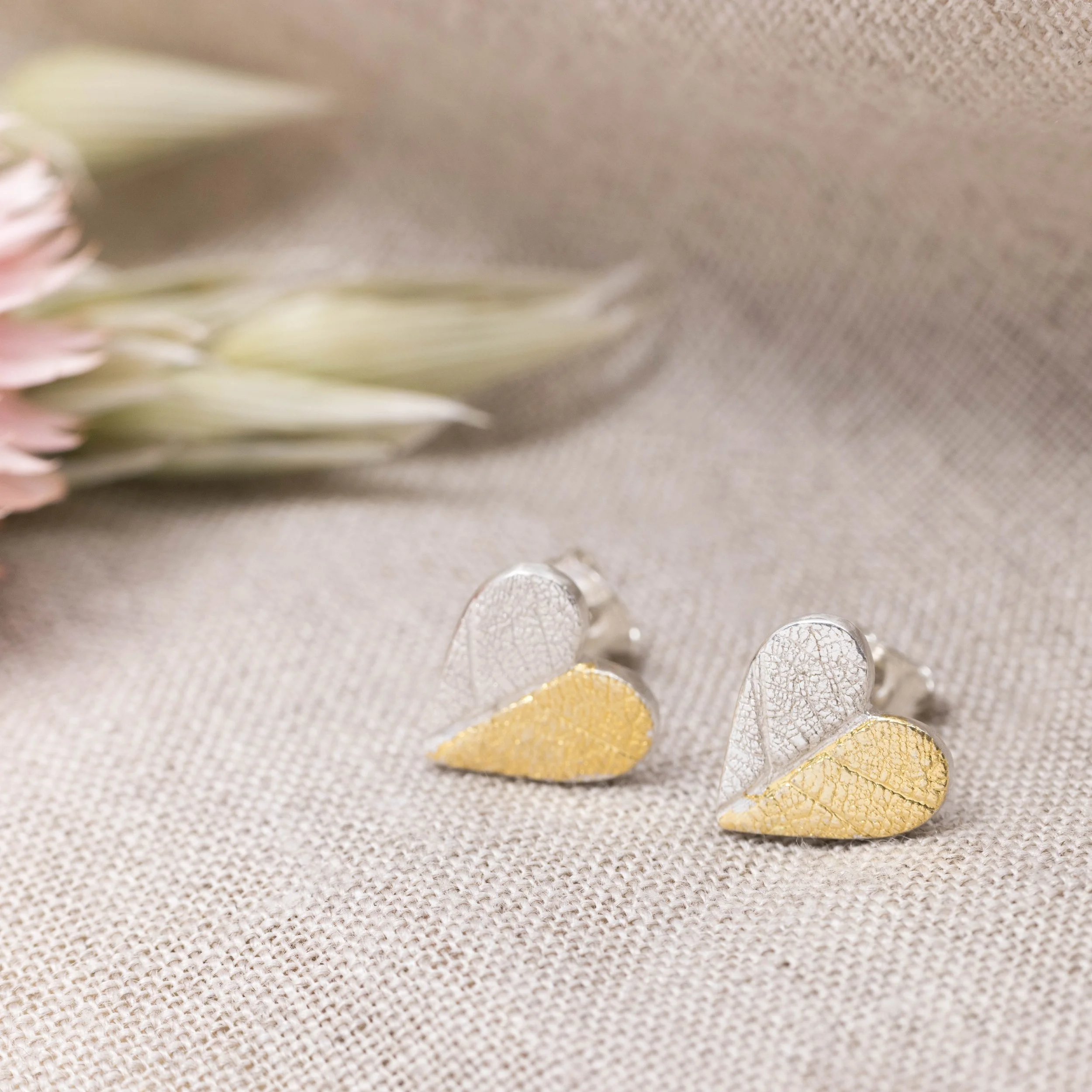Sterling silver heart-shaped stud earrings with textured leaf pattern and gold keum-boo accents.