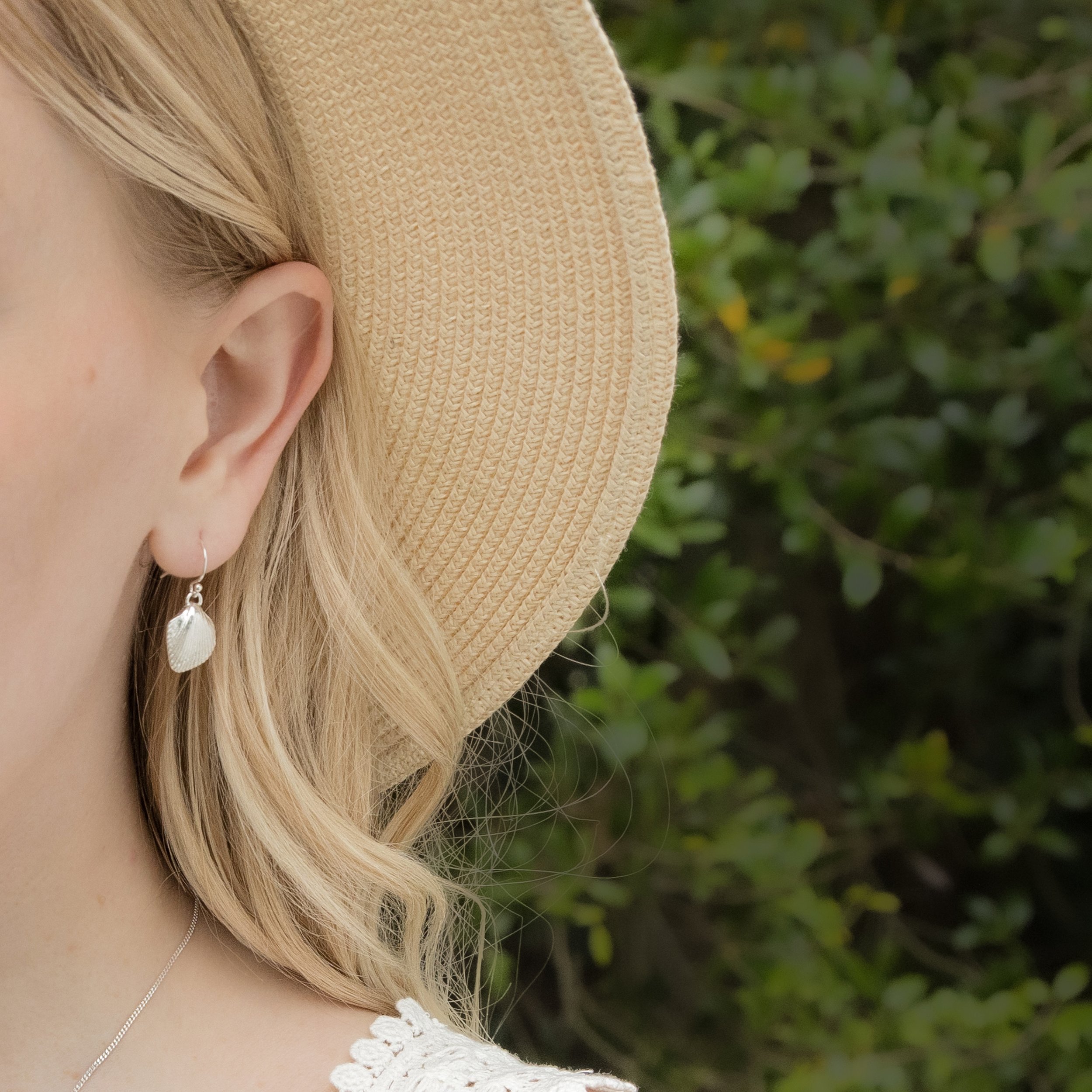 Sterling silver cockle shell drop earrings with detailed textured shells and polished finish, hanging from simple hook wires.