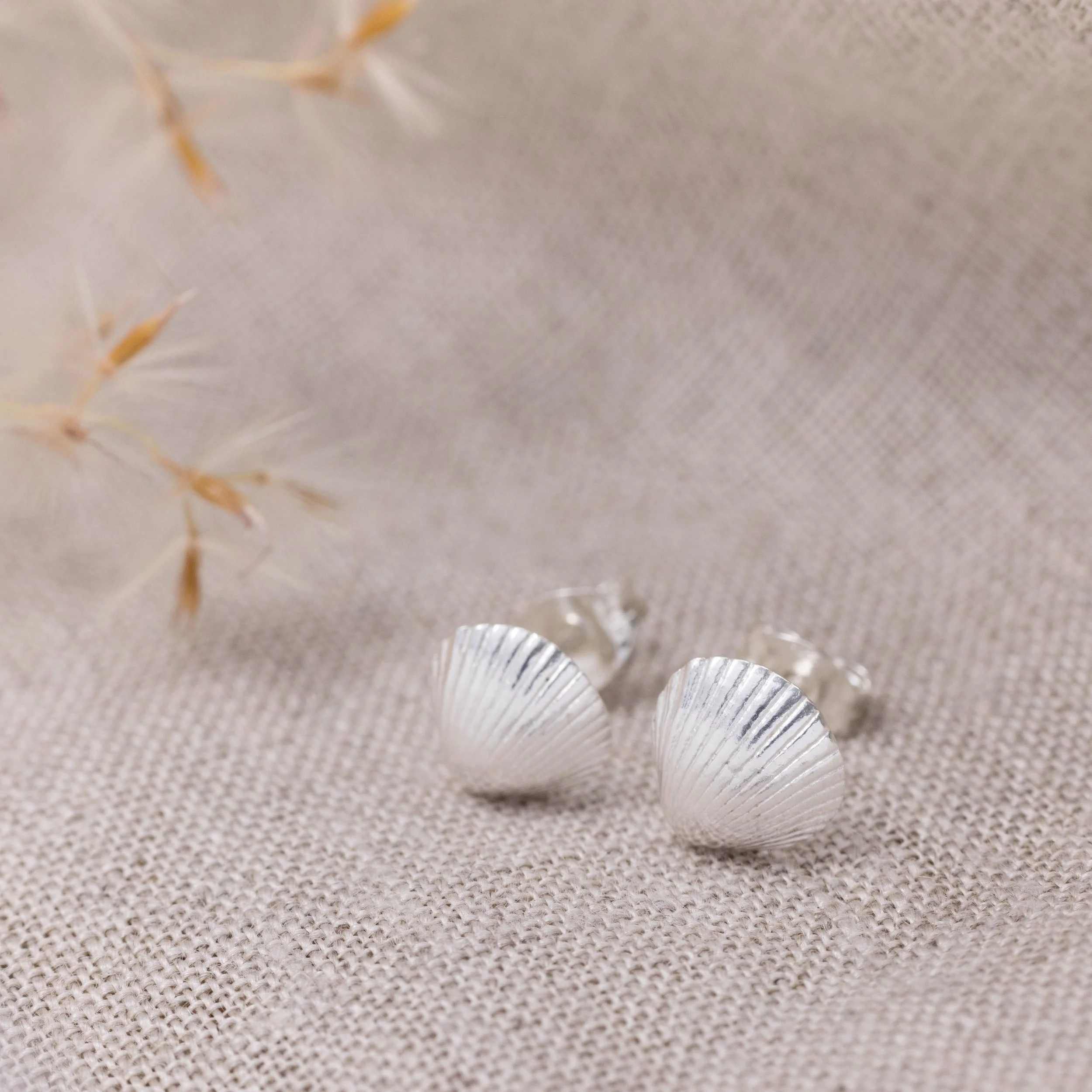 Sterling silver clamshell stud earrings with textured detailing, inspired by coastal seashells.