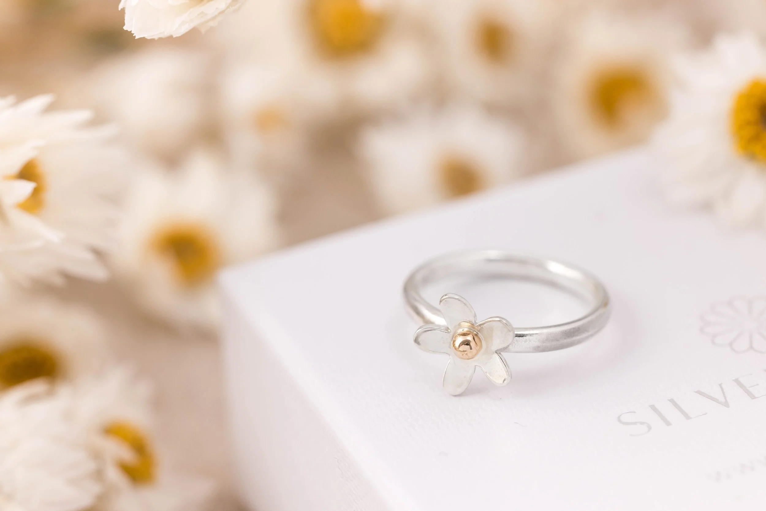 Sterling silver daisy ring with a polished band and detailed medium-sized flower design featuring 9ct gold stamen and a domed centre.