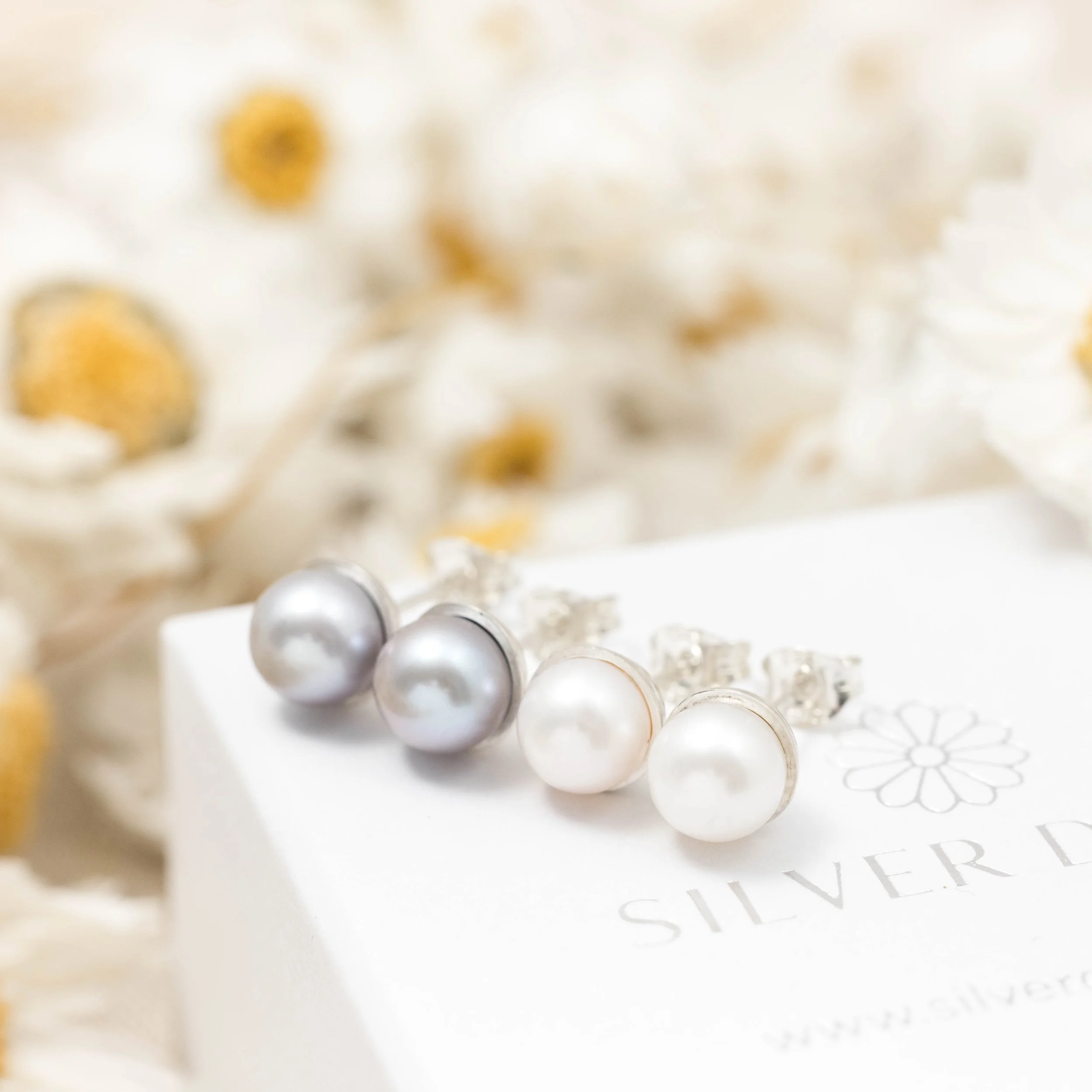 Round grey pearl stud earrings with smooth lustrous finish, set in handcrafted sterling silver cups finished with ear posts and scrolls.