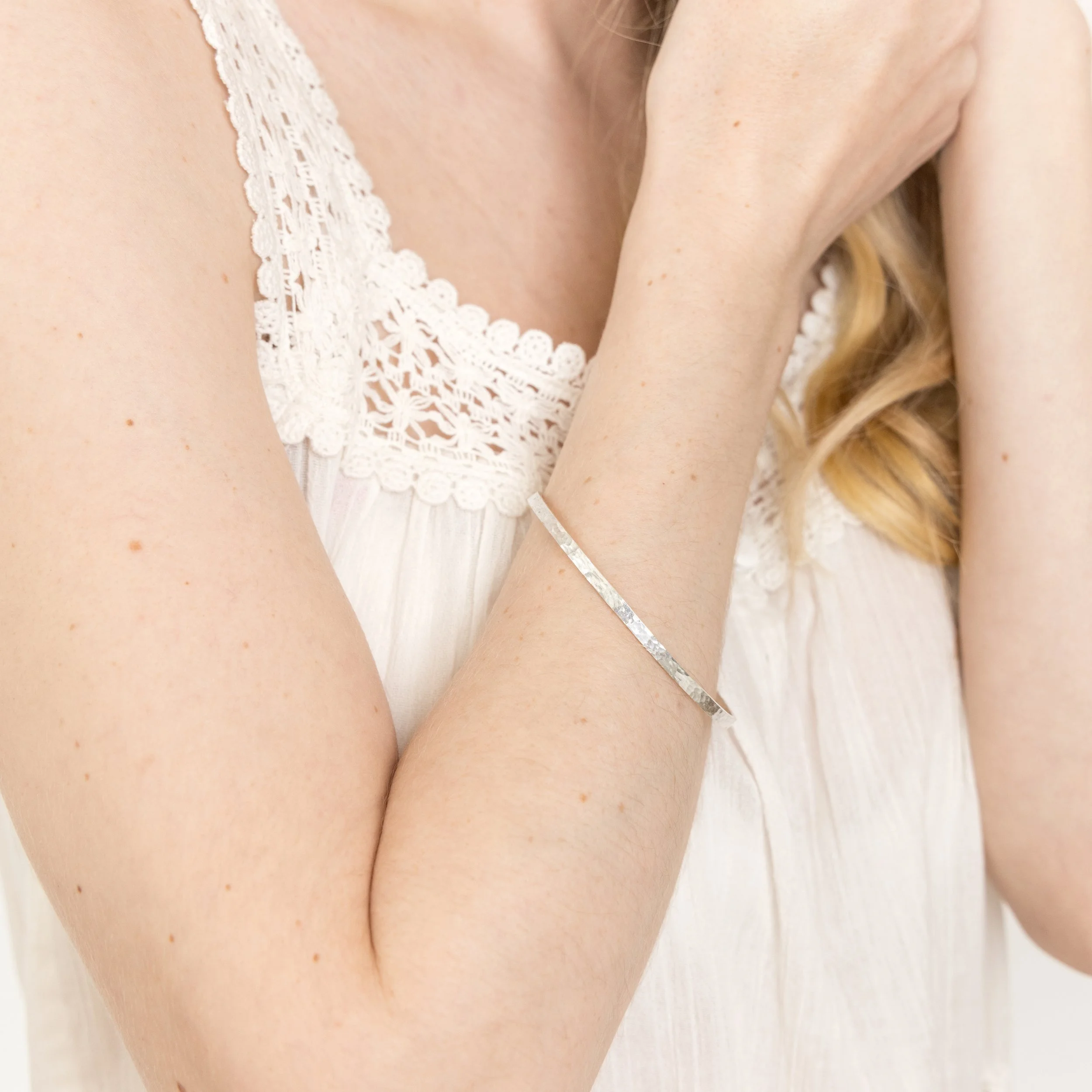 Sterling silver stacking bangle with a hammered dimple texture, polished finish, and minimalist contemporary design.