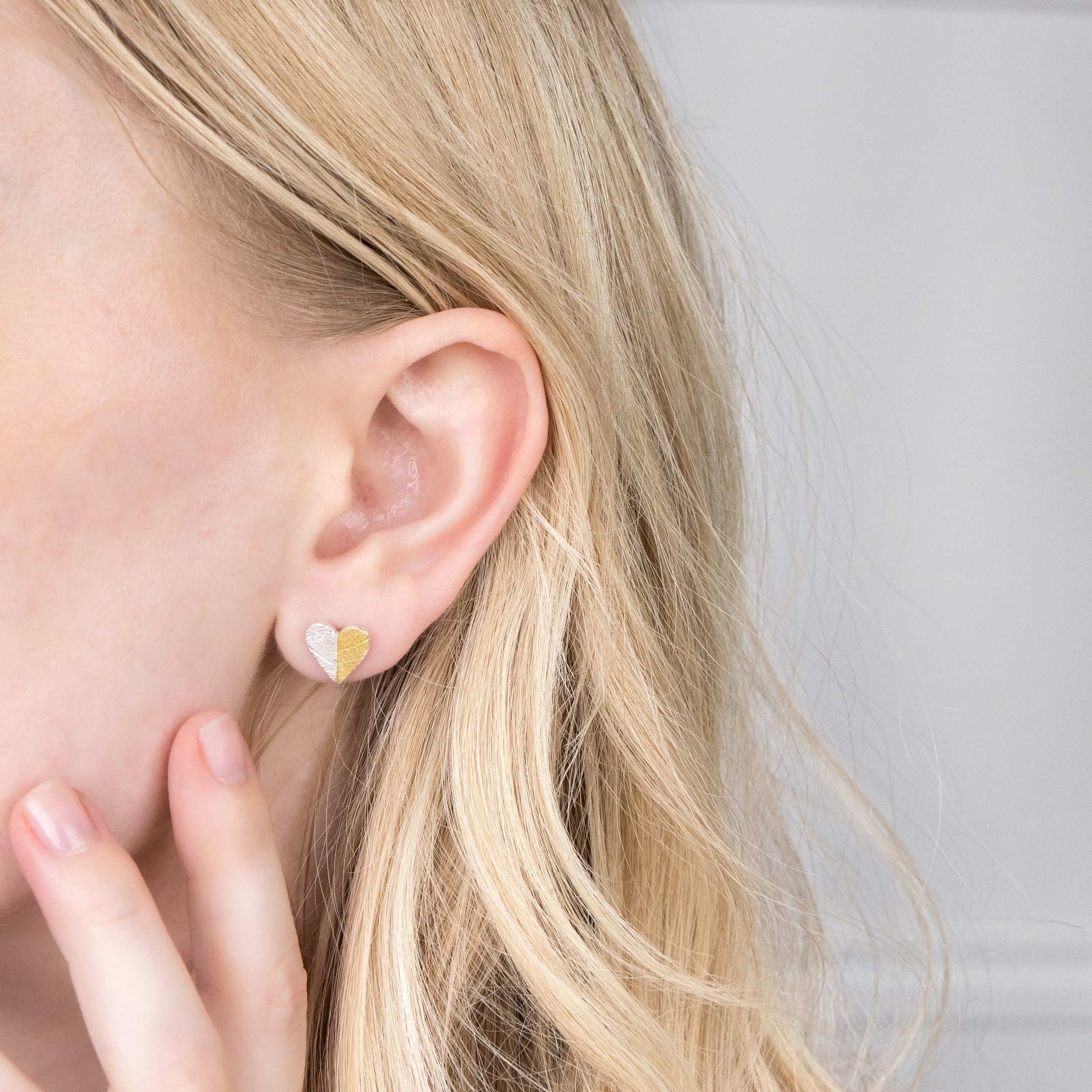 Sterling silver heart-shaped stud earrings with textured leaf pattern and gold keum-boo accents.