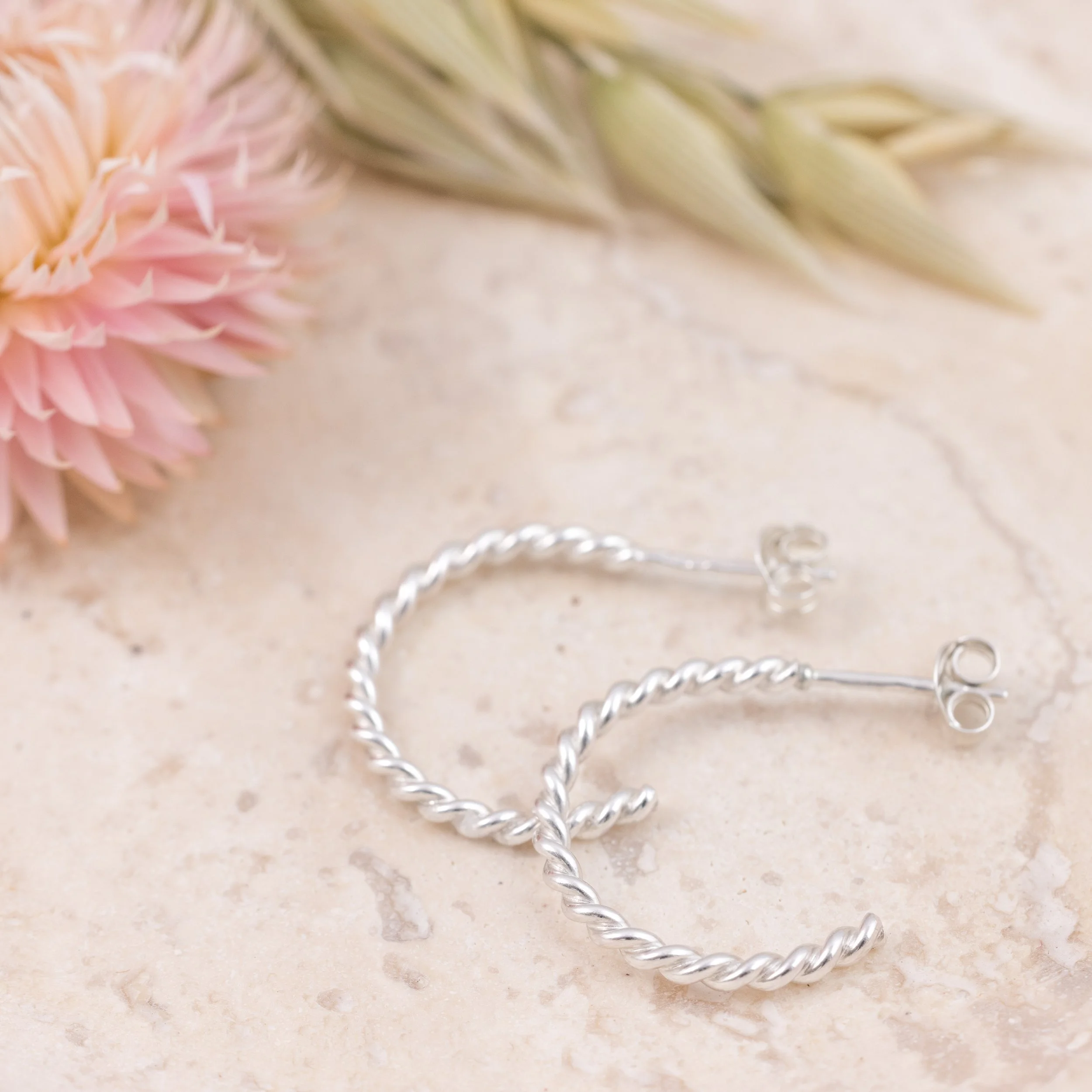 Polished sterling silver twist hoop earrings with a textured spiral design, lightweight and elegant for everyday wear.