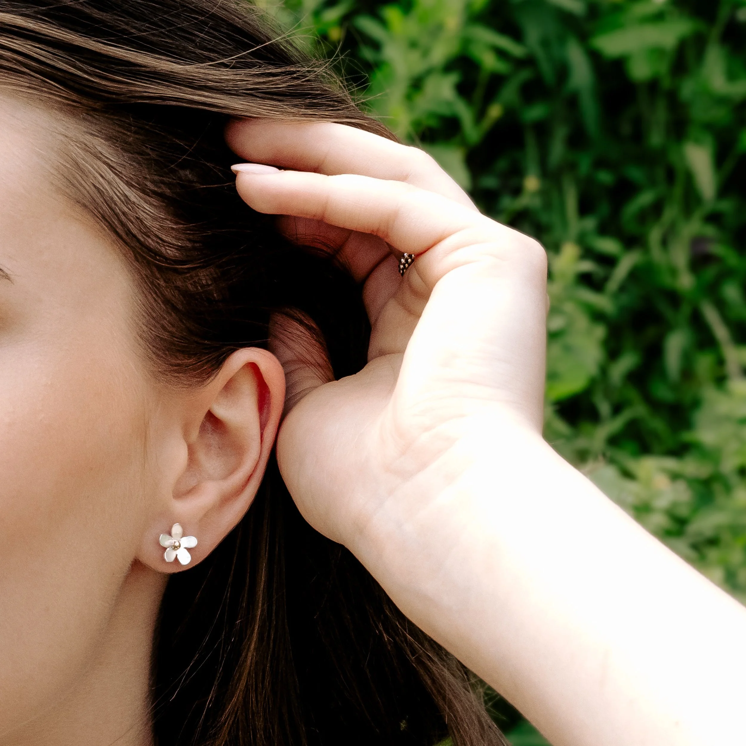 Handmade silver daisy stud earrings with polished petals and 9ct gold stamen centres.