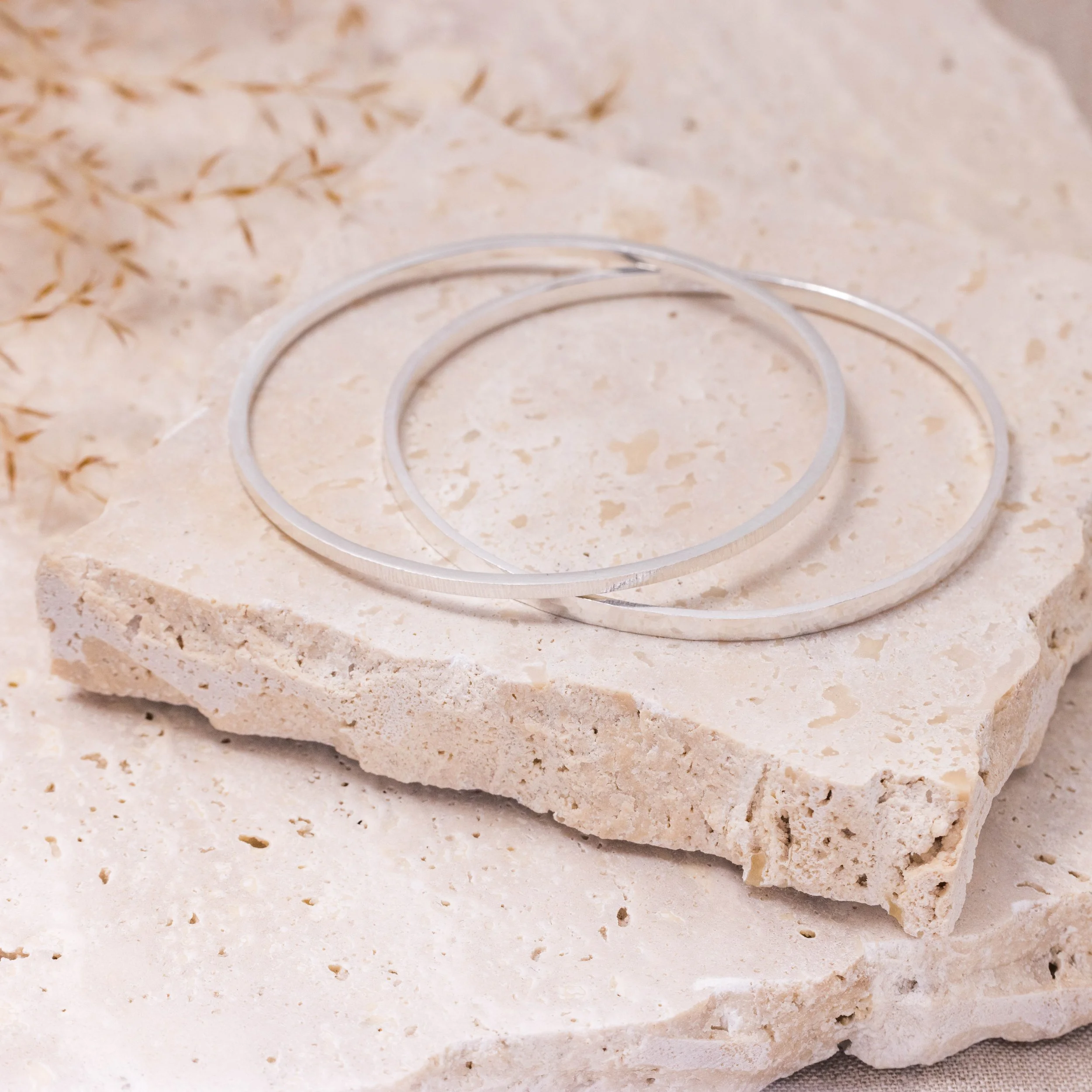 Sterling silver stacking bangle with a hammered dimple texture, polished finish, and minimalist contemporary design.