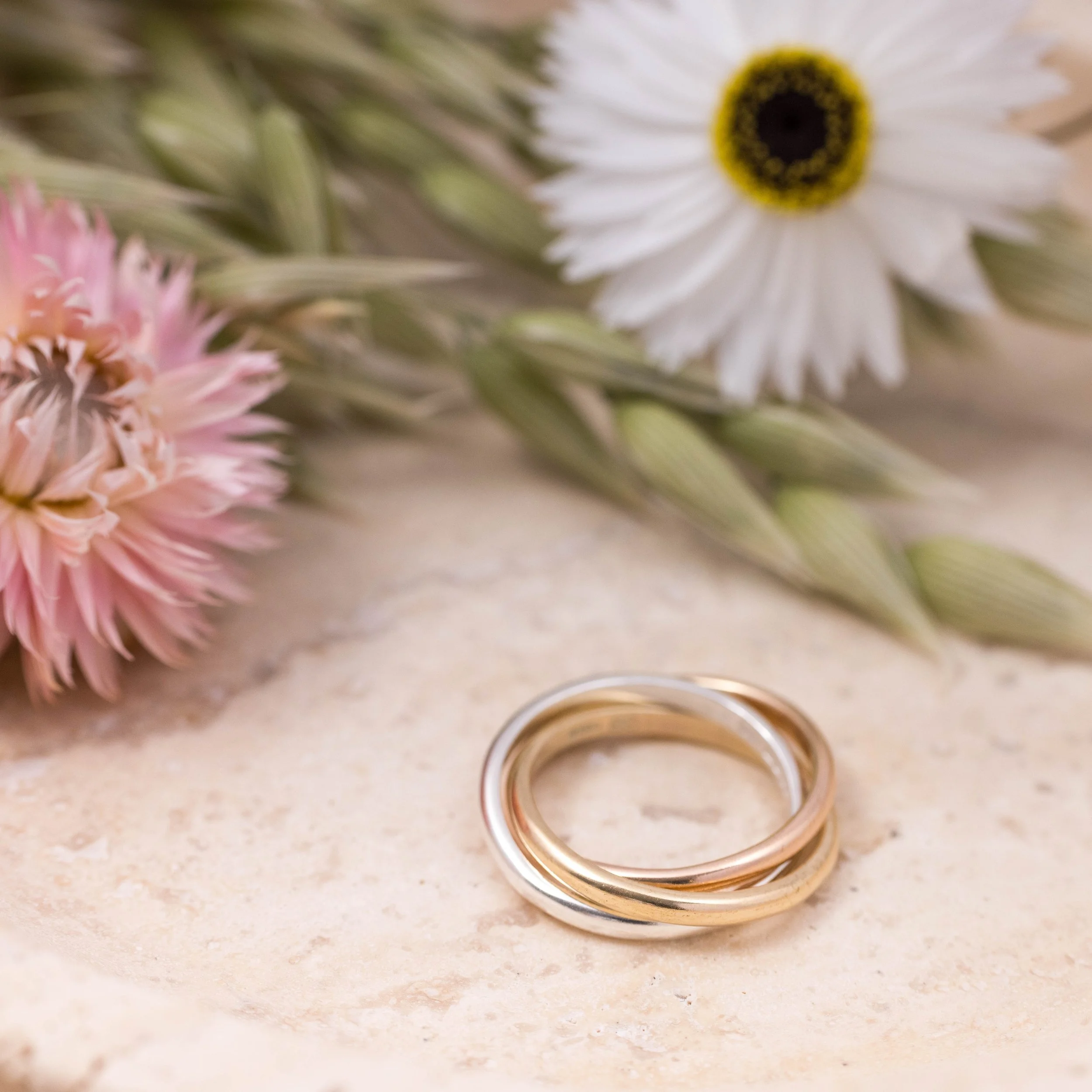 9ct gold & sterling silver trinity ring featuring interlocking silver, yellow and rose gold bands with a polished finish. Also known as a russian wedding ring.