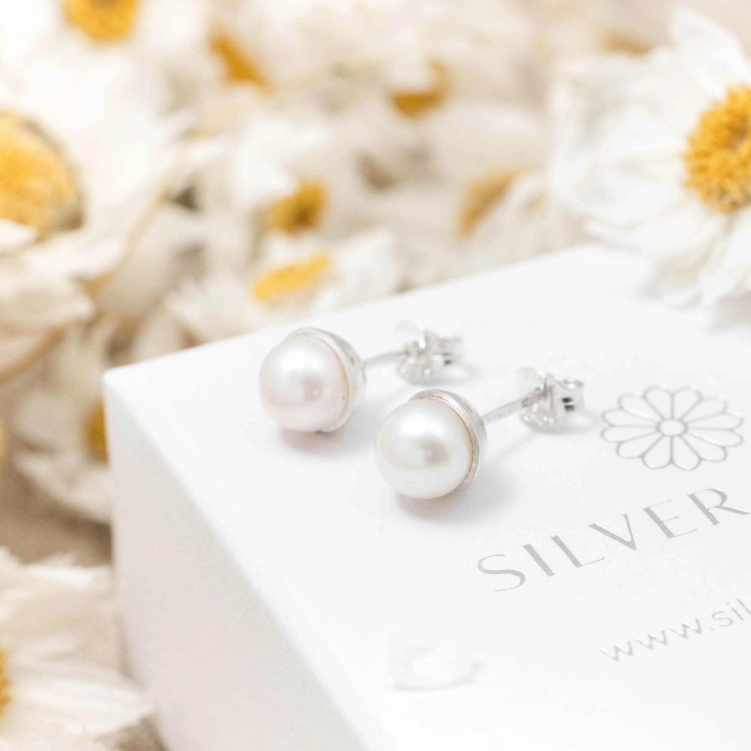 Round ivory freshwater pearl stud earrings with smooth lustrous finish set in handcrafted sterling silver cups with ear post and scroll backs.