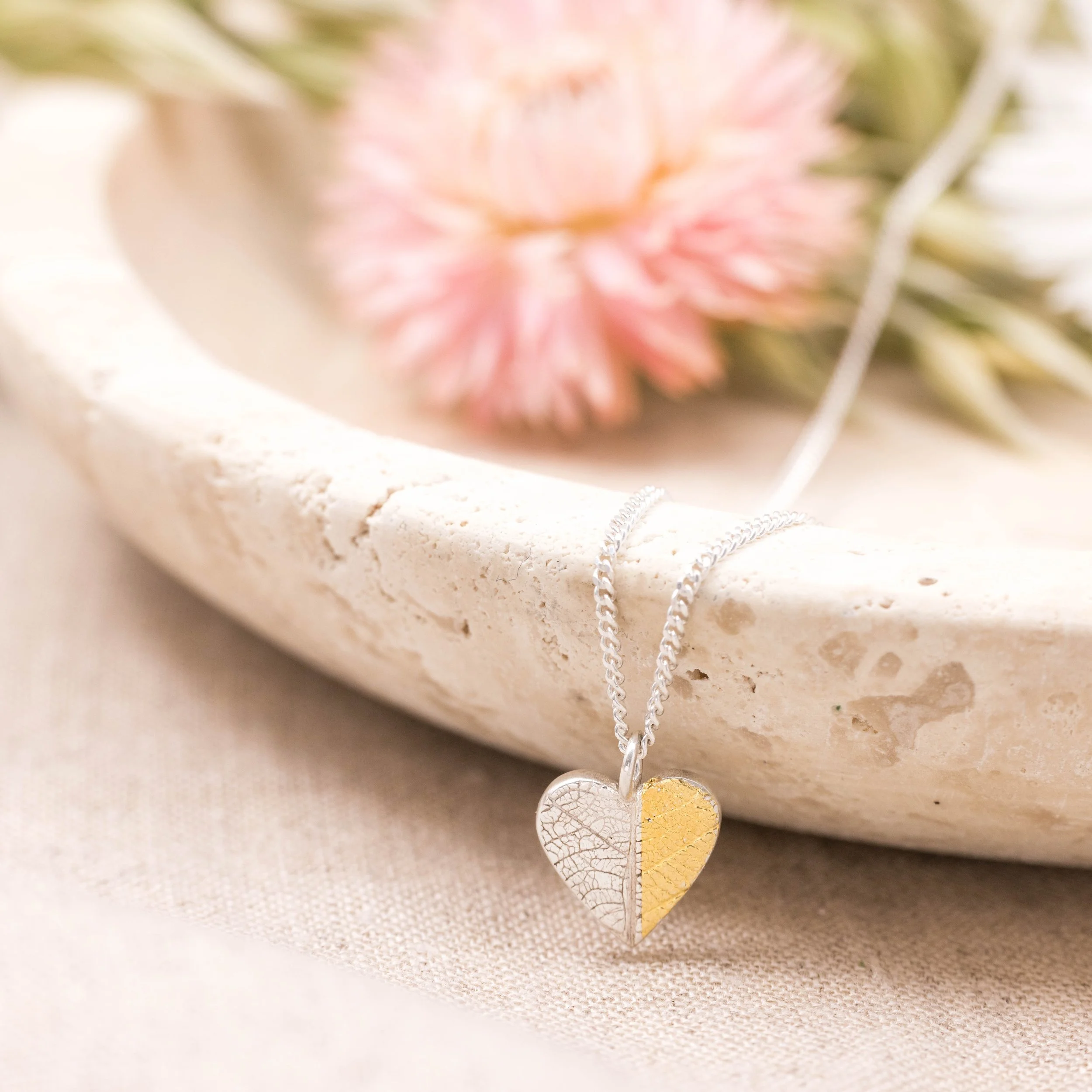 Gold and silver heart leaf pendant necklace with textured leaf pattern on a fine silver chain, handmade botanical jewellery.