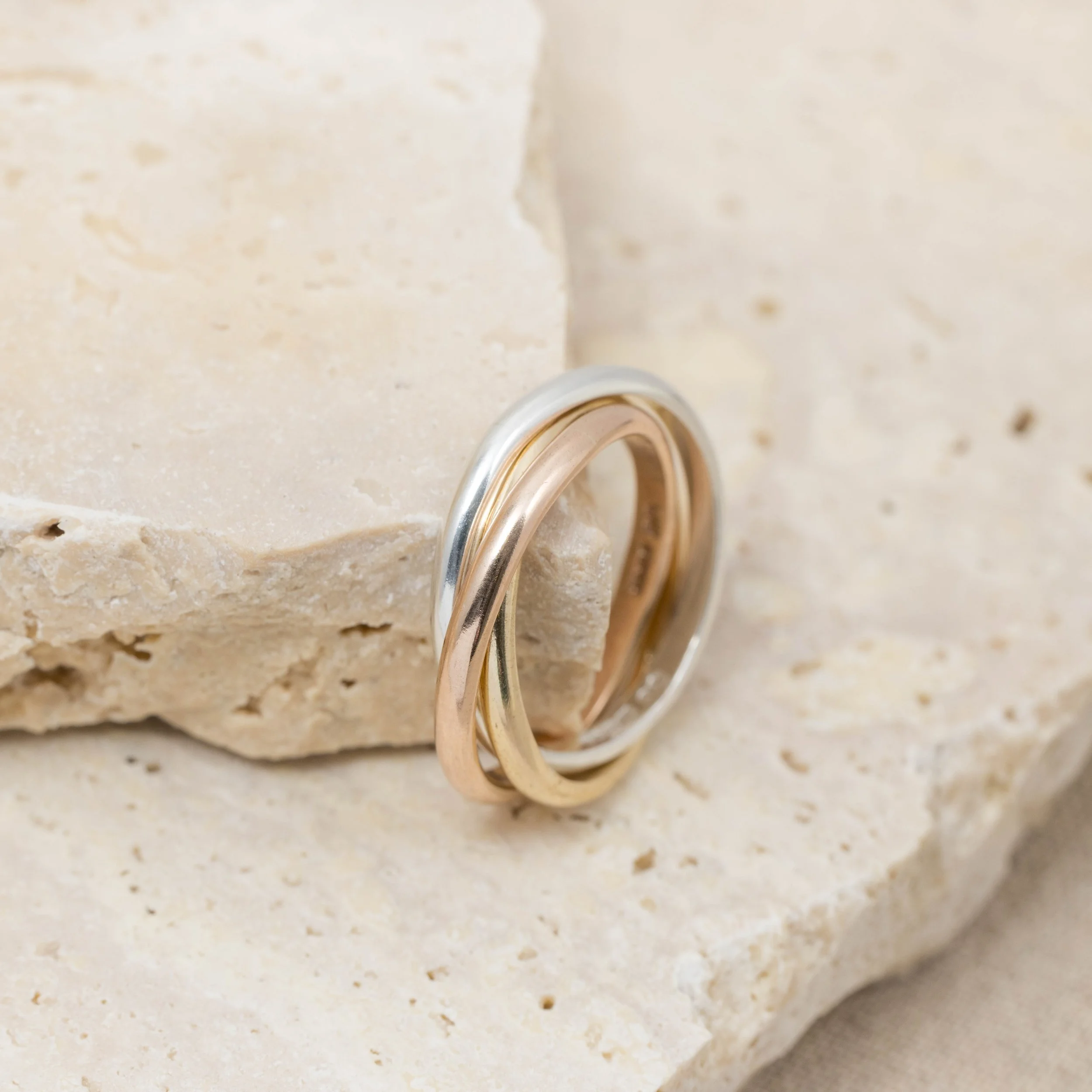 9ct gold tricolour trinity ring featuring interlocking yellow, white, and rose gold bands with a polished finish.