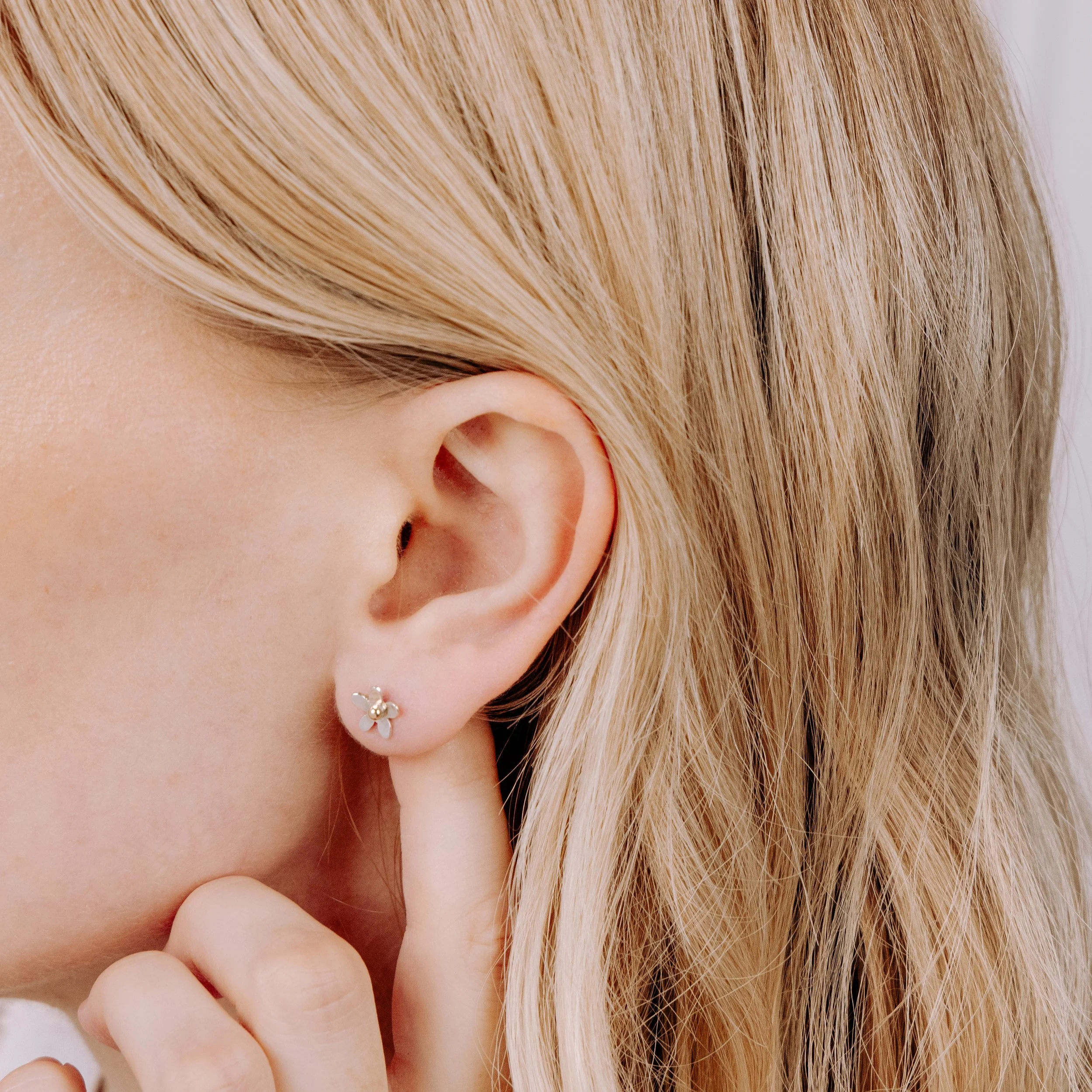 Small sterling silver daisy stud earrings with polished petals and 9ct gold stamen centres.