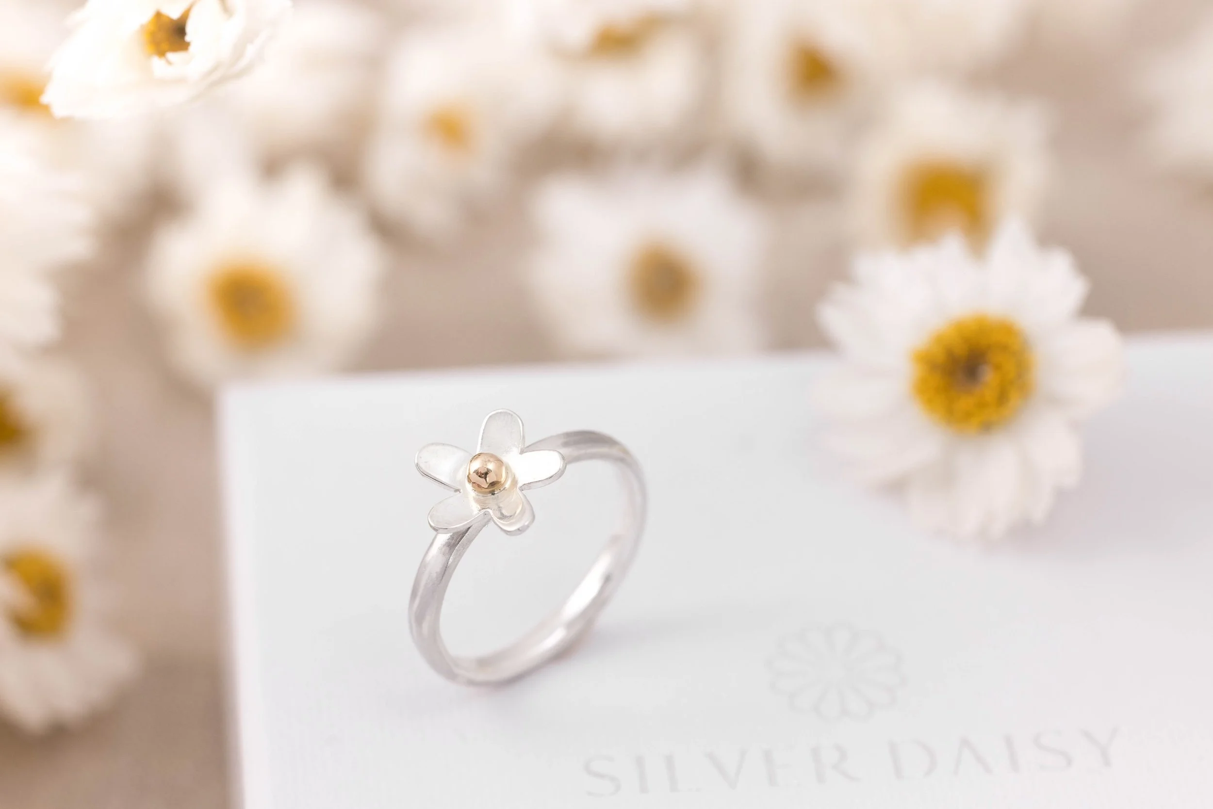 Sterling silver daisy ring with a polished band and detailed medium-sized flower design featuring 9ct gold stamen and a domed centre.