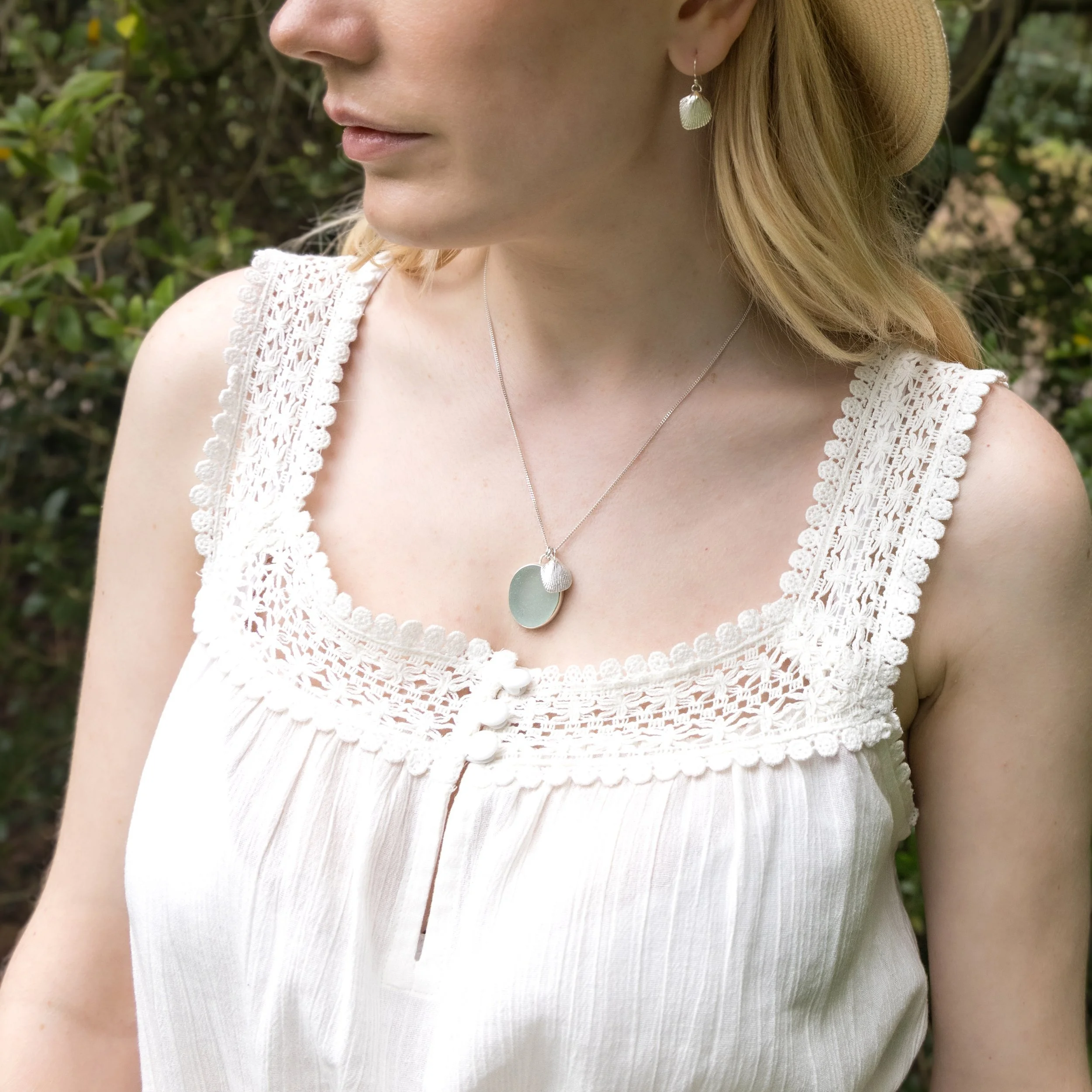 Sterling silver cockle shell drop earrings with detailed textured shells and polished finish, hanging from simple hook wires.