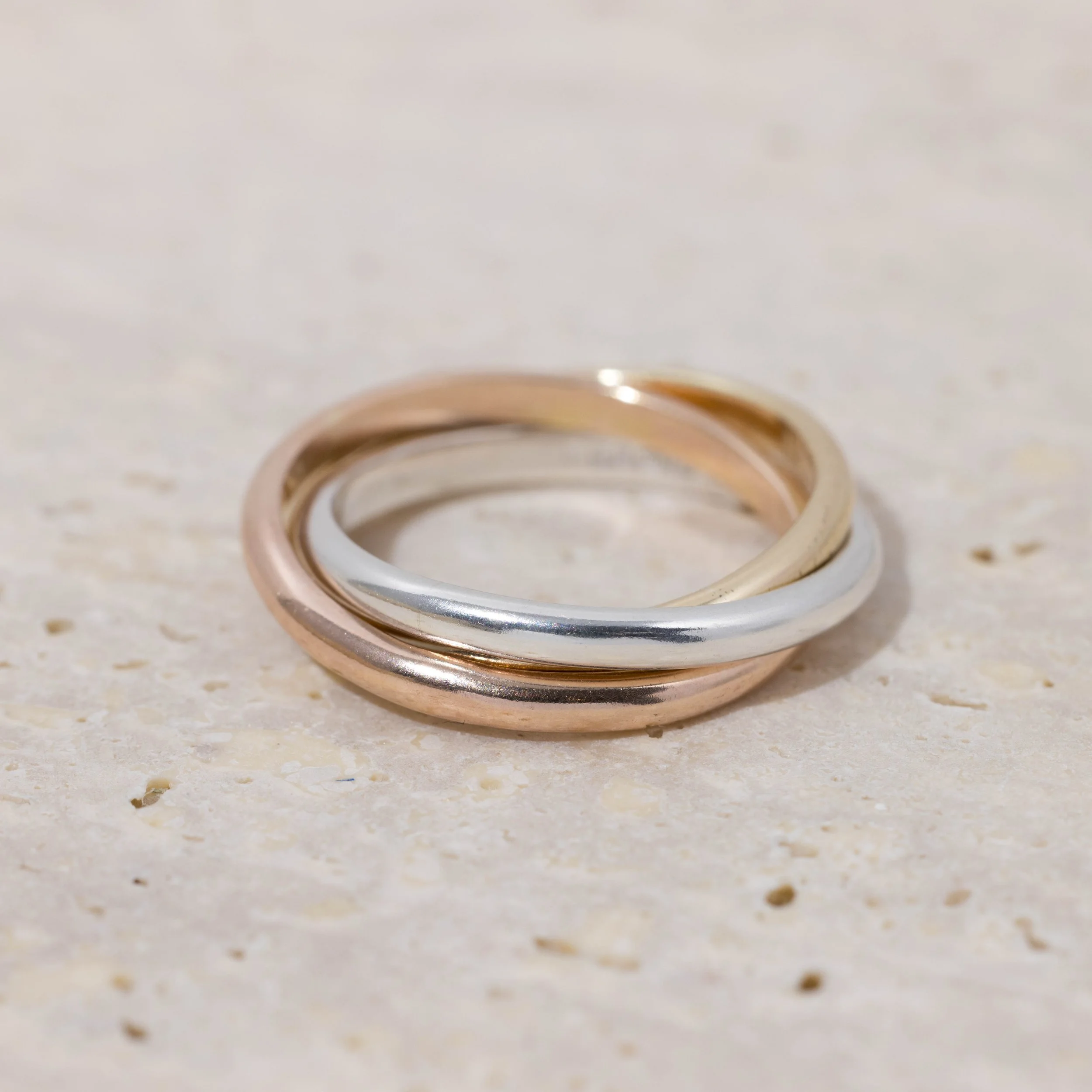 9ct gold & sterling silver trinity ring featuring interlocking silver, yellow and rose gold bands with a polished finish. Also known as a russian wedding ring.