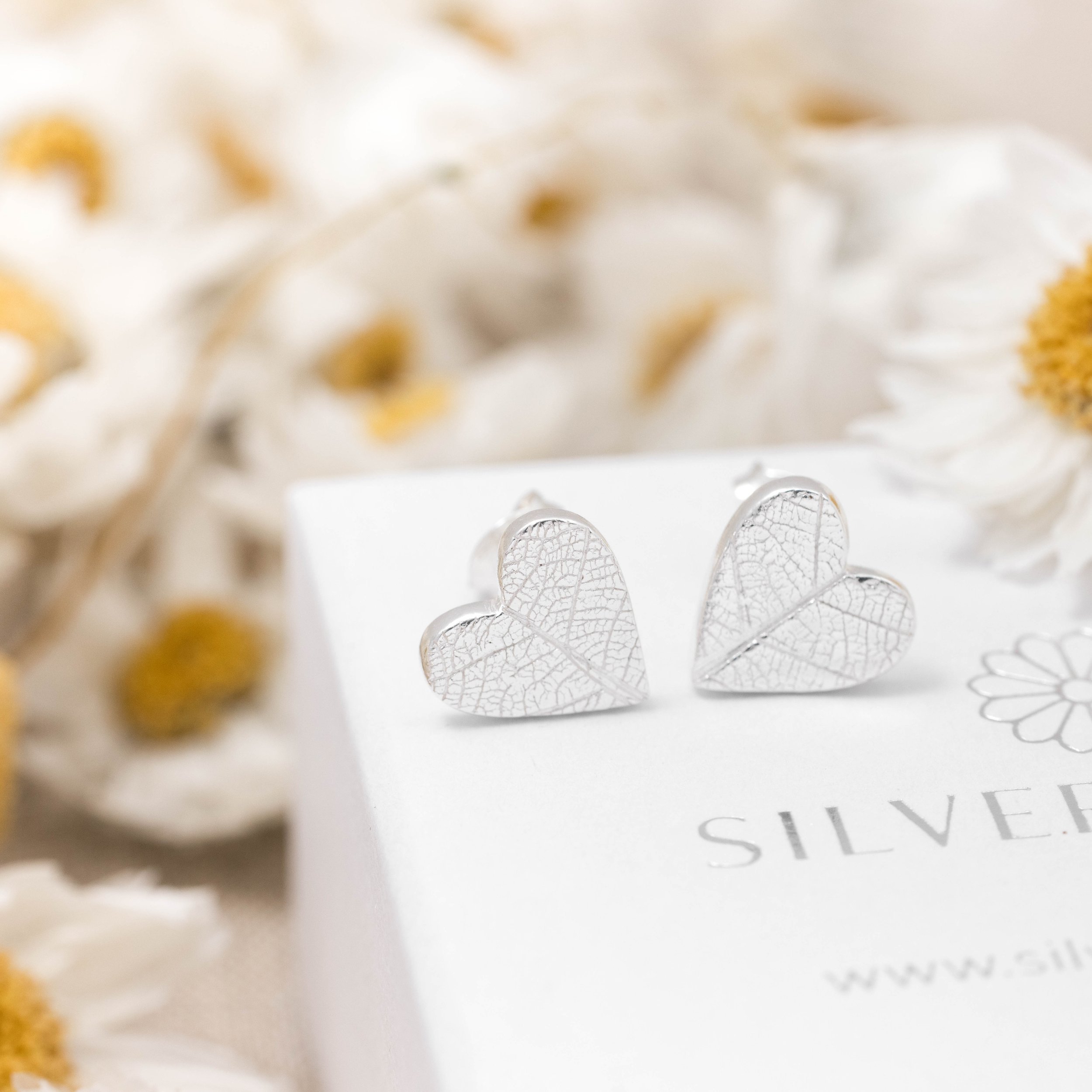 Sterling silver heart stud earrings with delicate imprinted leaf texture on a polished finish.