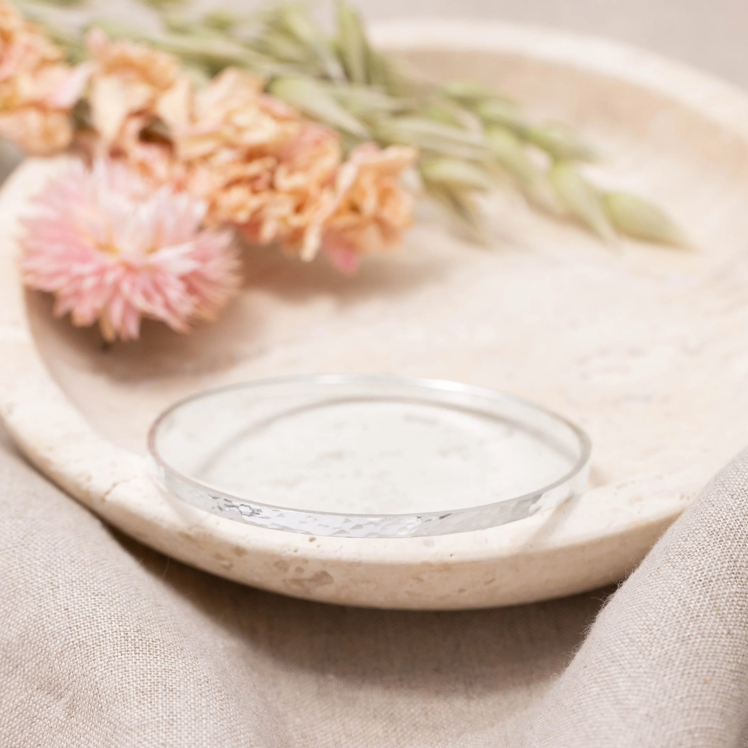 Sterling silver stacking bangle with a hammered dimple texture, polished finish, and minimalist contemporary design.