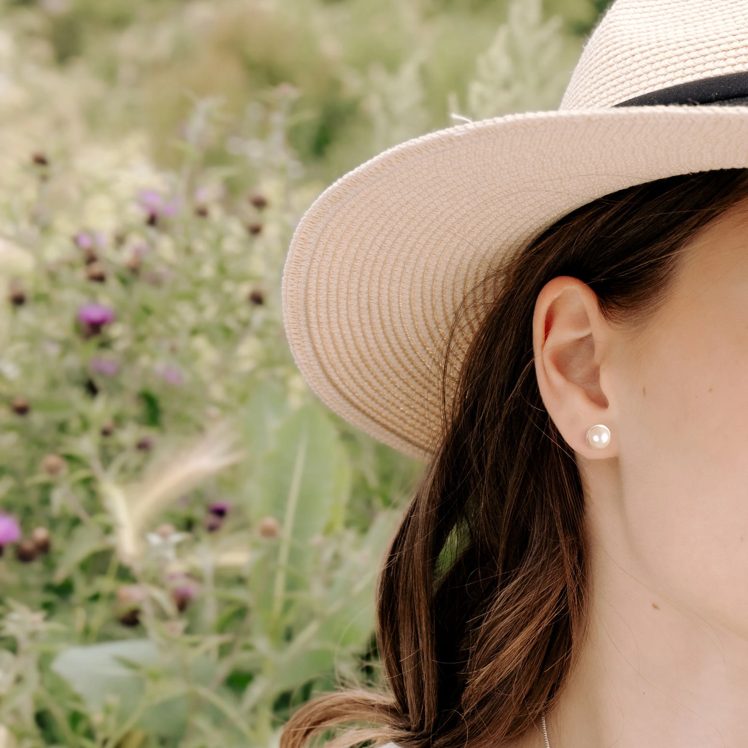 Round ivory freshwater pearl stud earrings with smooth lustrous finish set in handcrafted sterling silver cups with ear post and scroll backs.