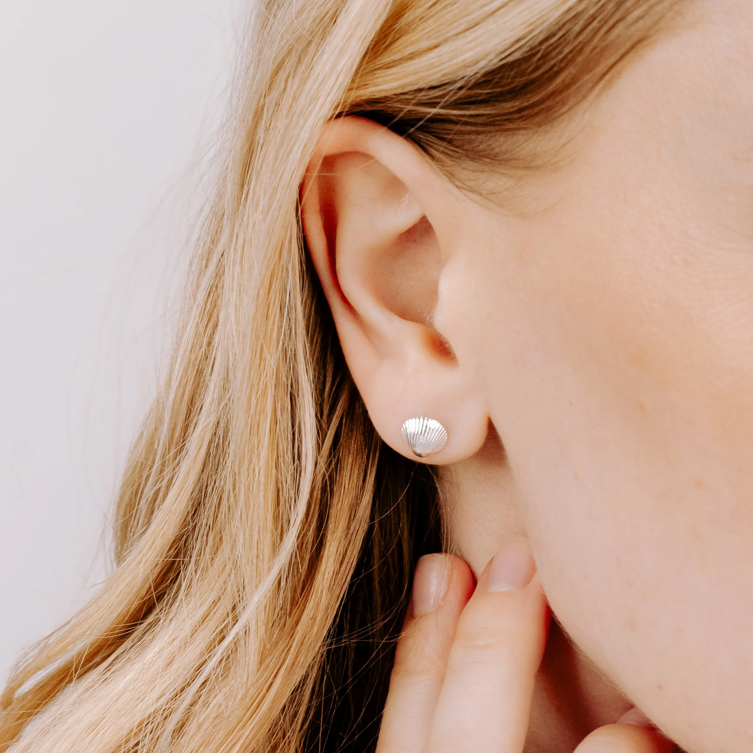 Sterling silver clamshell stud earrings with textured detailing, inspired by coastal seashells.