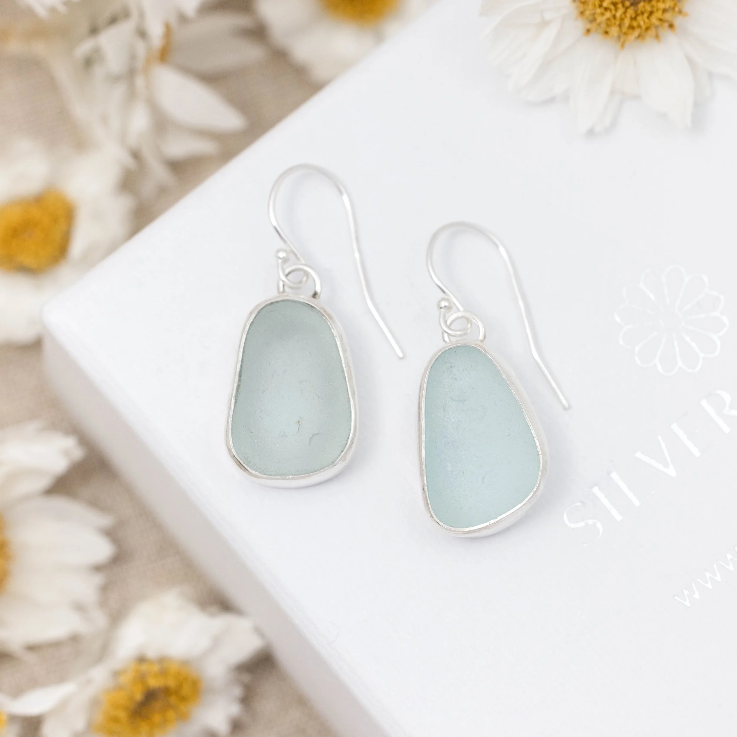 Sterling silver drop earrings with smooth aqua sea glass pebbles and minimalist ear wires, coastal inspired jewellery design.