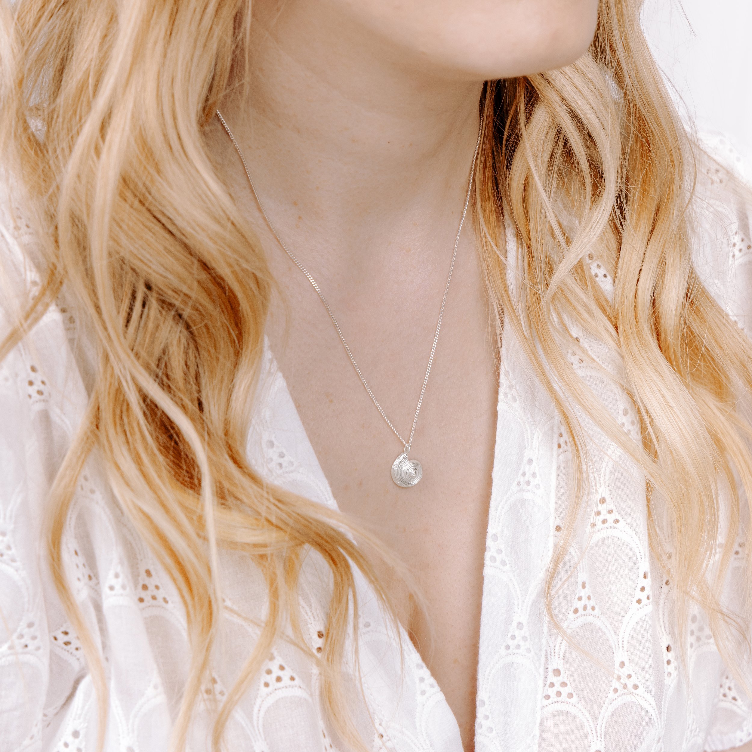 Sterling silver pendant necklace with a detailed fossil ammonite design on a fine chain, inspired by coastal and seaside jewellery.