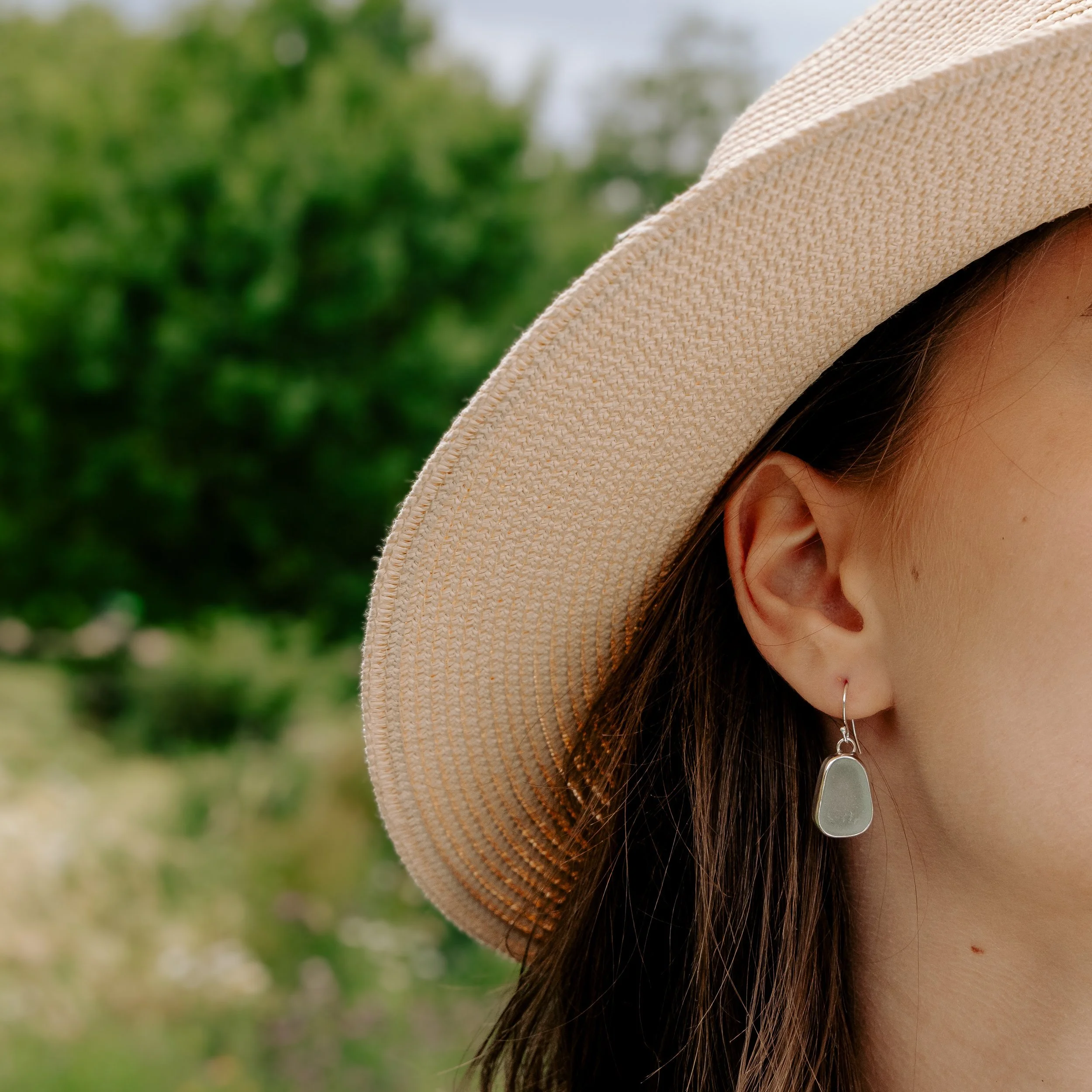 Sterling silver drop earrings with smooth aqua sea glass pebbles and minimalist ear wires, coastal inspired jewellery design.
