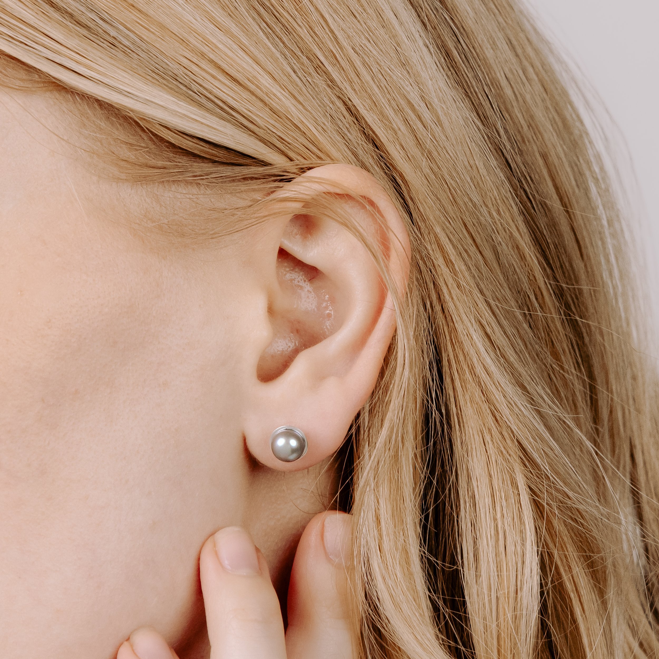 Round grey pearl stud earrings with smooth lustrous finish, set in handcrafted sterling silver cups finished with ear posts and scrolls.