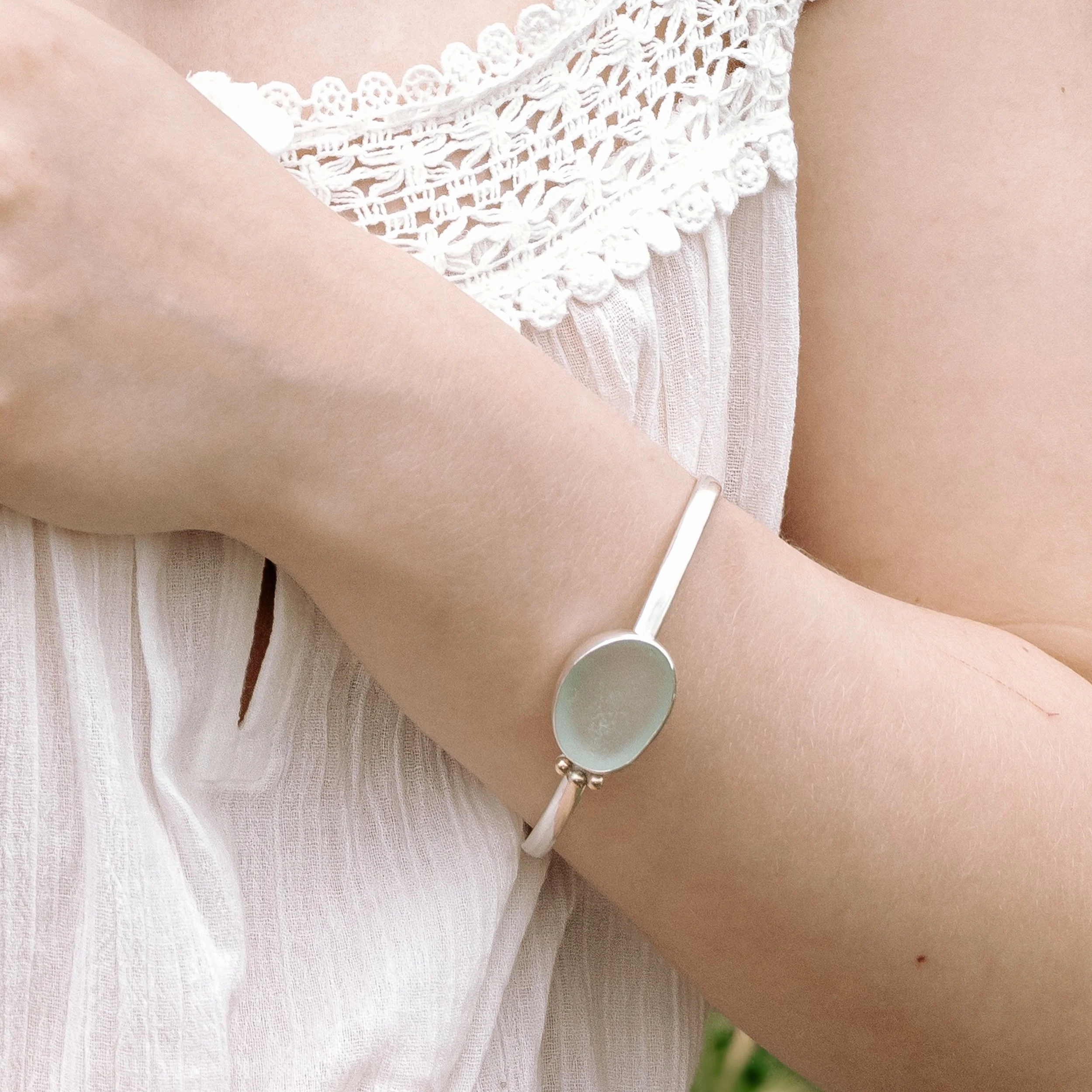 Aquamarine sea glass pebble set with a sterling silver setting and oval band bangle. 9ct gold granulation to highlight. Highly polished finished for this coastal inspired design.