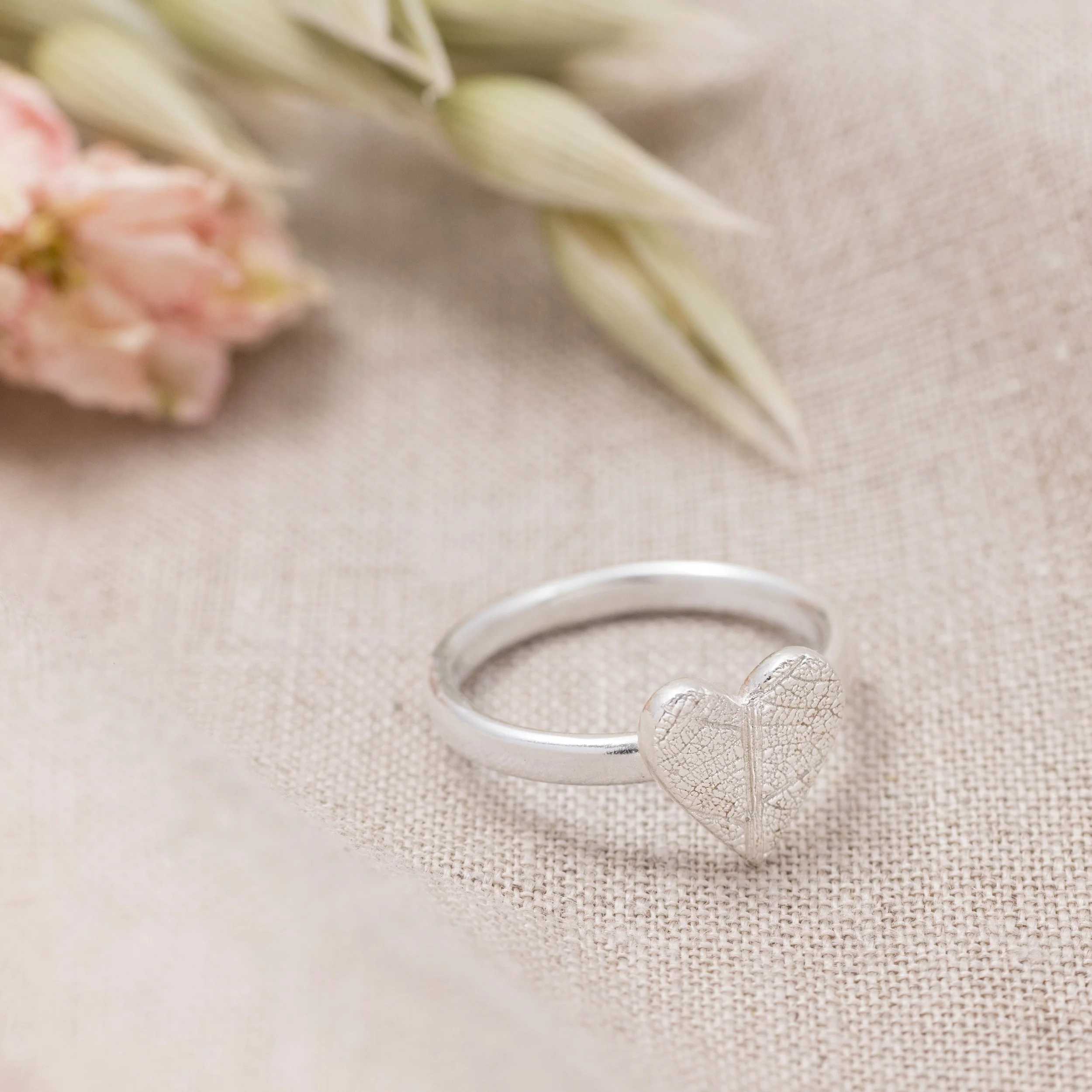 Sterling silver heart-shaped ring with delicate pressed leaf pattern on a polished band.