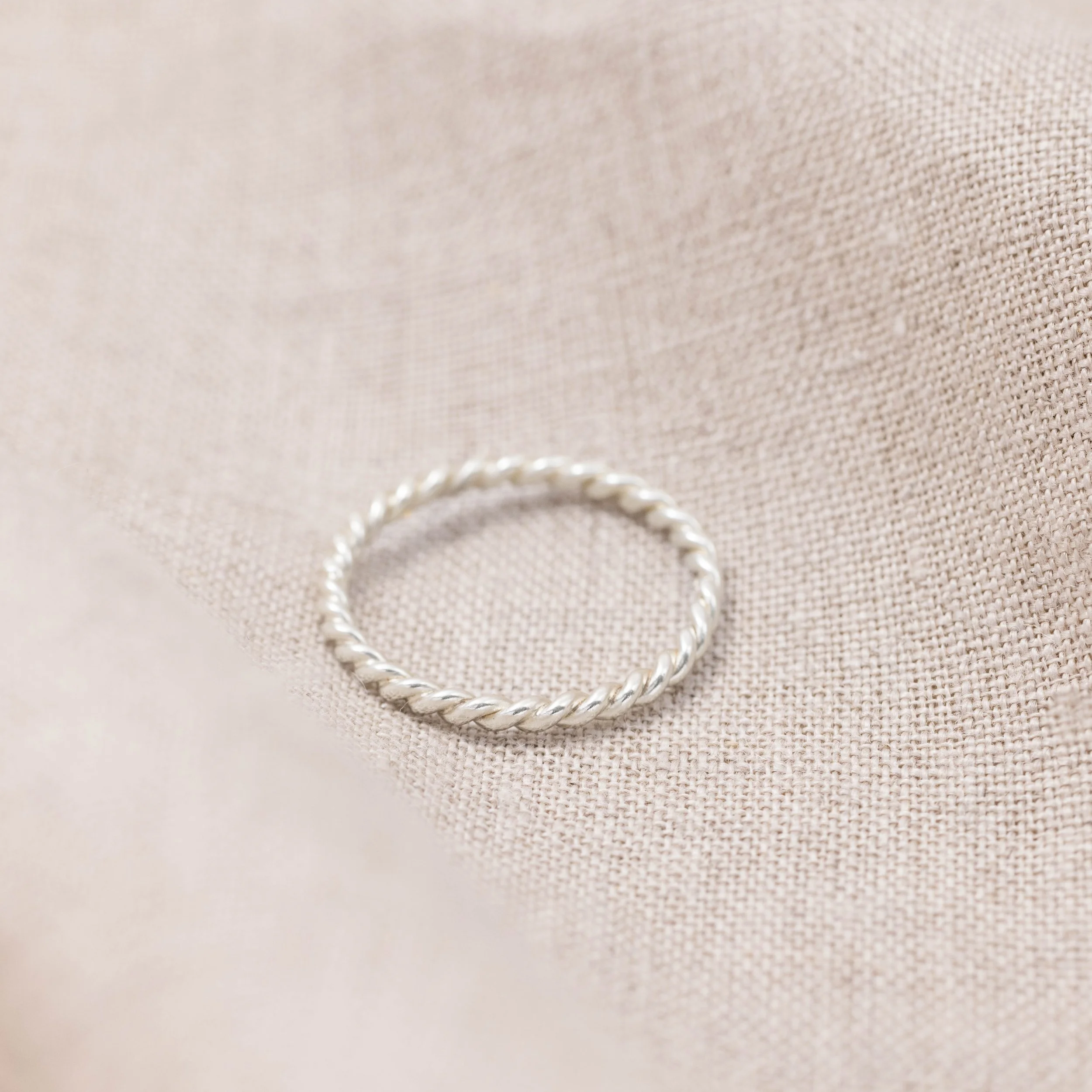 Delicate 9ct white gold twist stacking ring with a polished rope design, ideal for layering or wearing as a minimalist band.