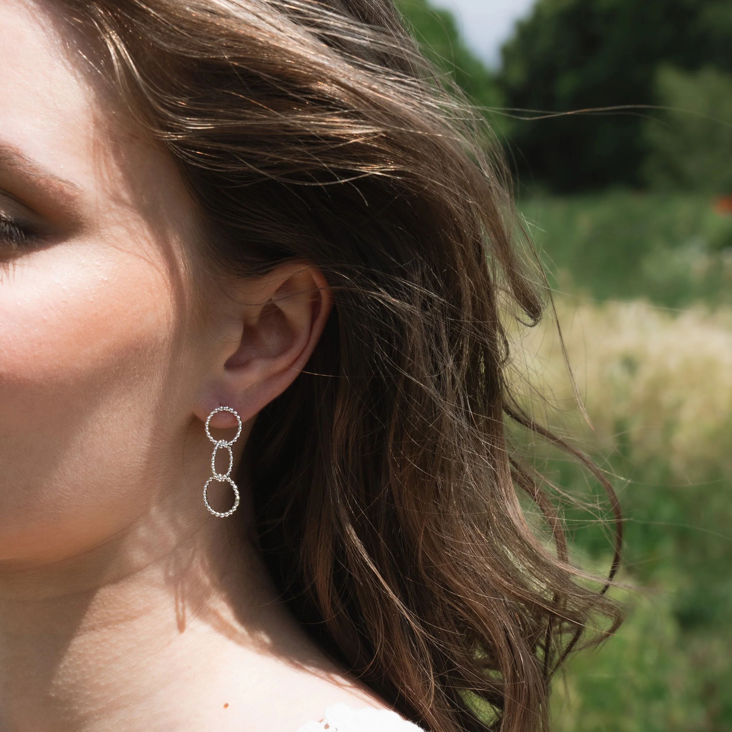 Sterling silver multi-hoop earrings with polished bead accents and textured loops arranged in a layered, contemporary design.