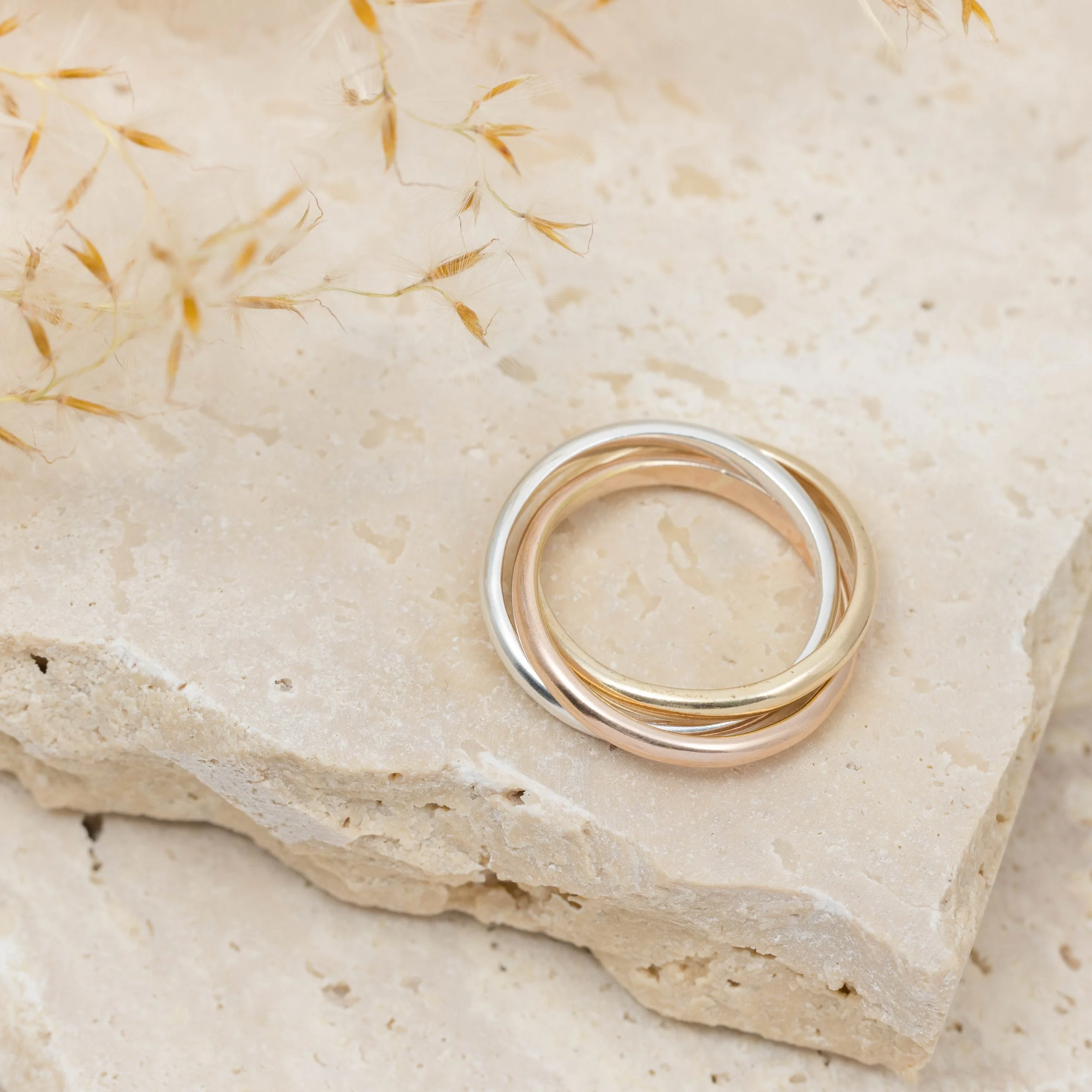 9ct gold tricolour trinity ring featuring interlocking yellow, white, and rose gold bands with a polished finish.