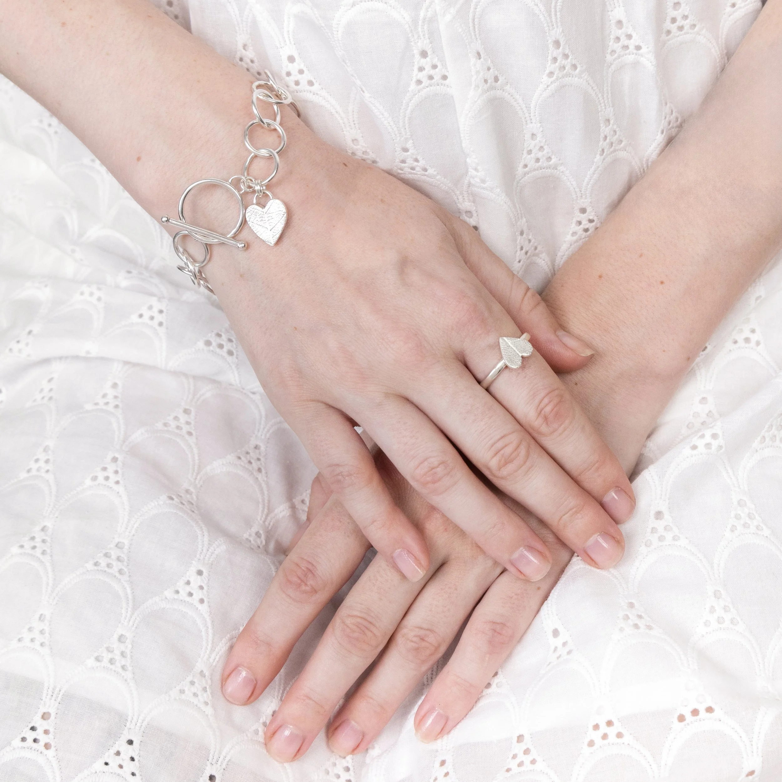 Sterling silver bracelet with a textured heart charm featuring a delicate leaf pattern, finished with a toggle clasp.