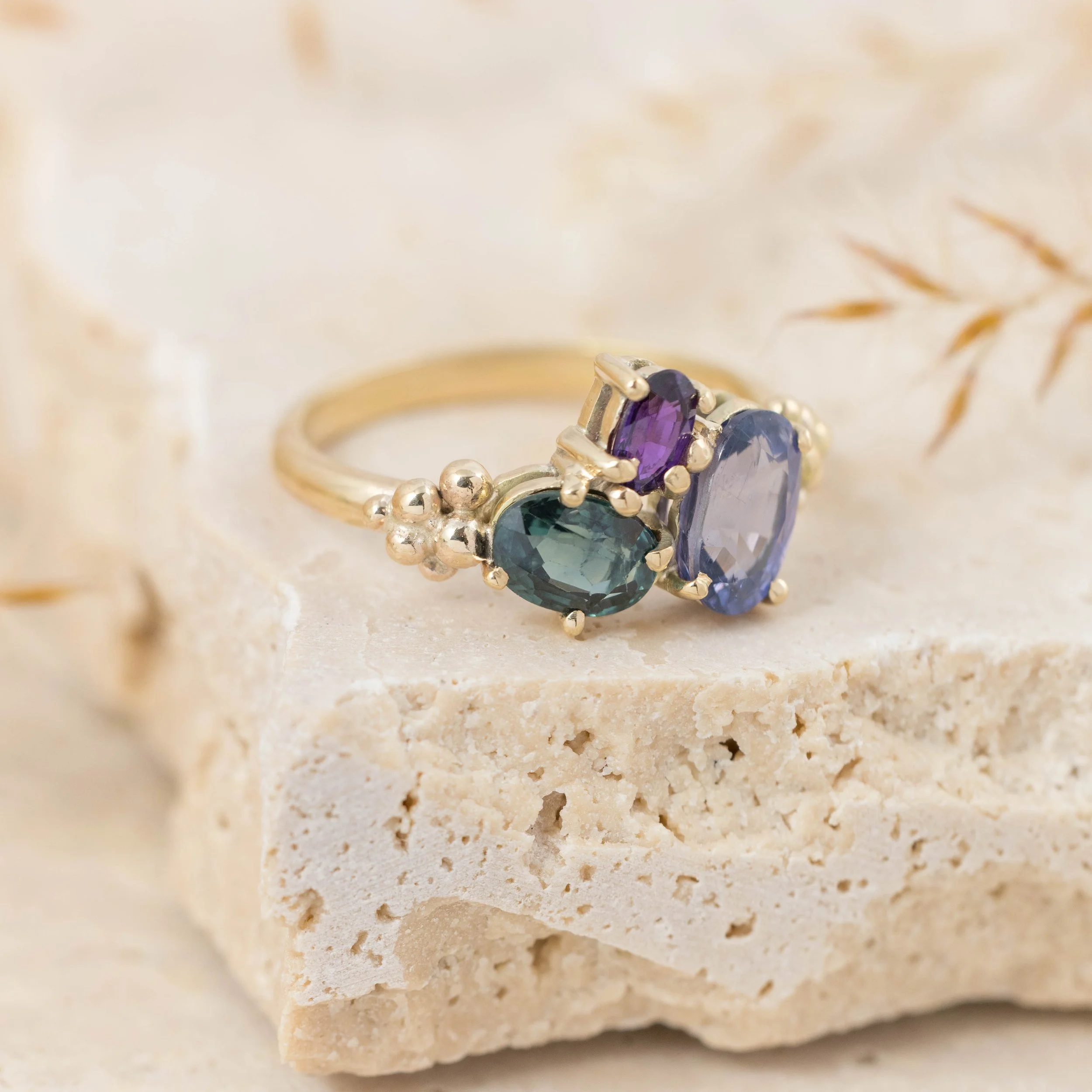 Yellow gold ring with a cluster of sparkling saaphires in teal, deep blue, and purple. Inspired by the colours of the aurora borealis.