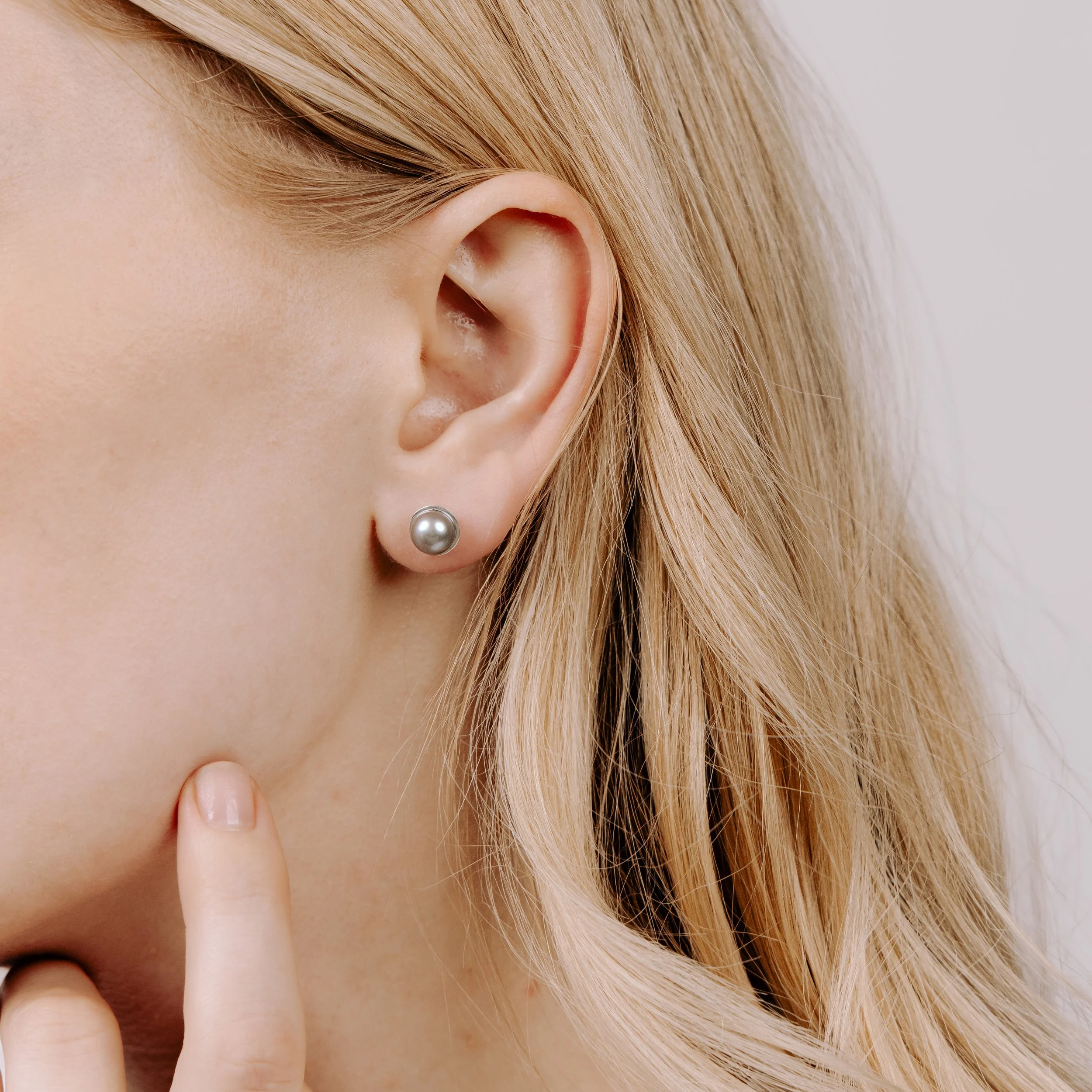 Round grey pearl stud earrings with smooth lustrous finish, set in handcrafted sterling silver cups finished with ear posts and scrolls.