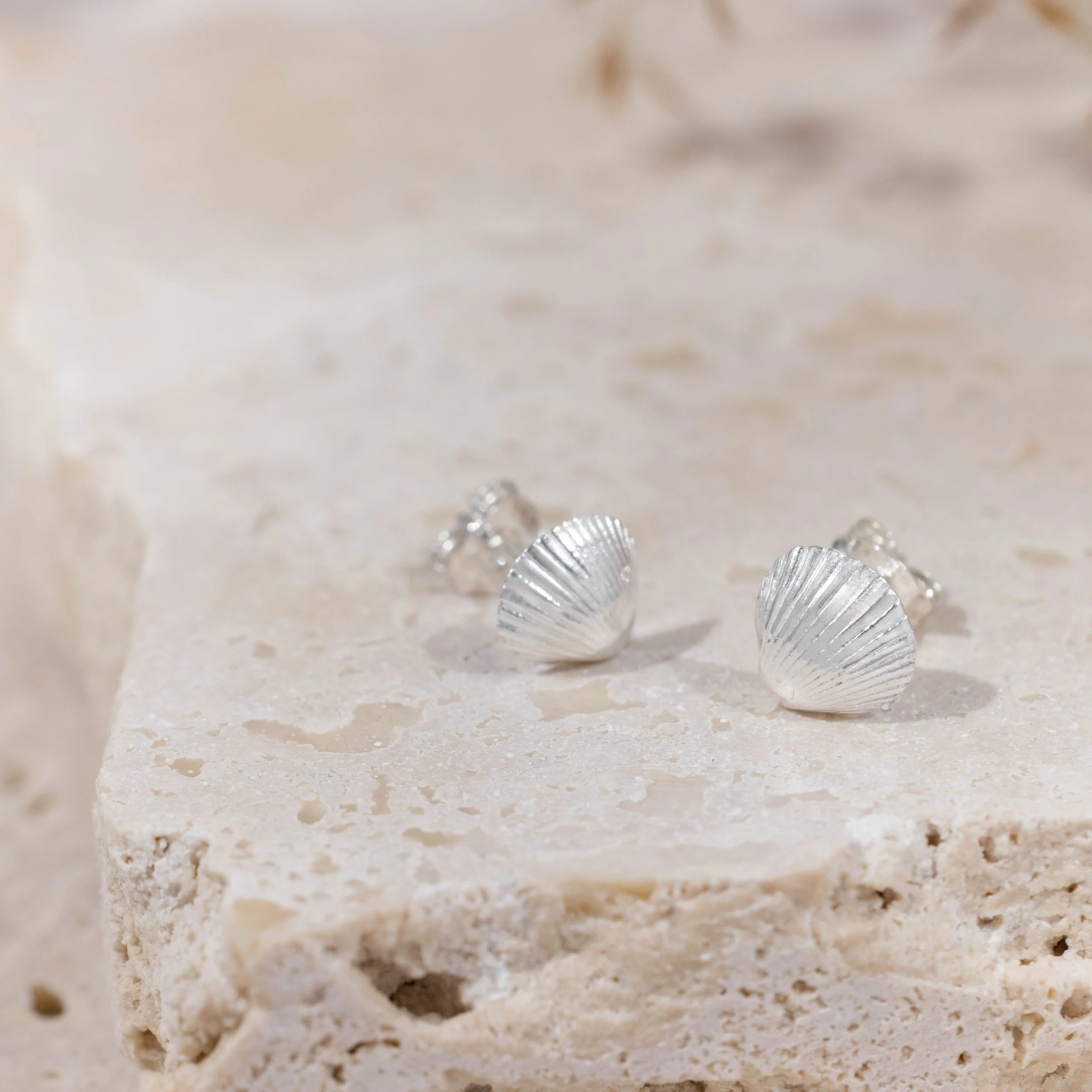 Sterling silver clamshell stud earrings with textured detailing, inspired by coastal seashells.